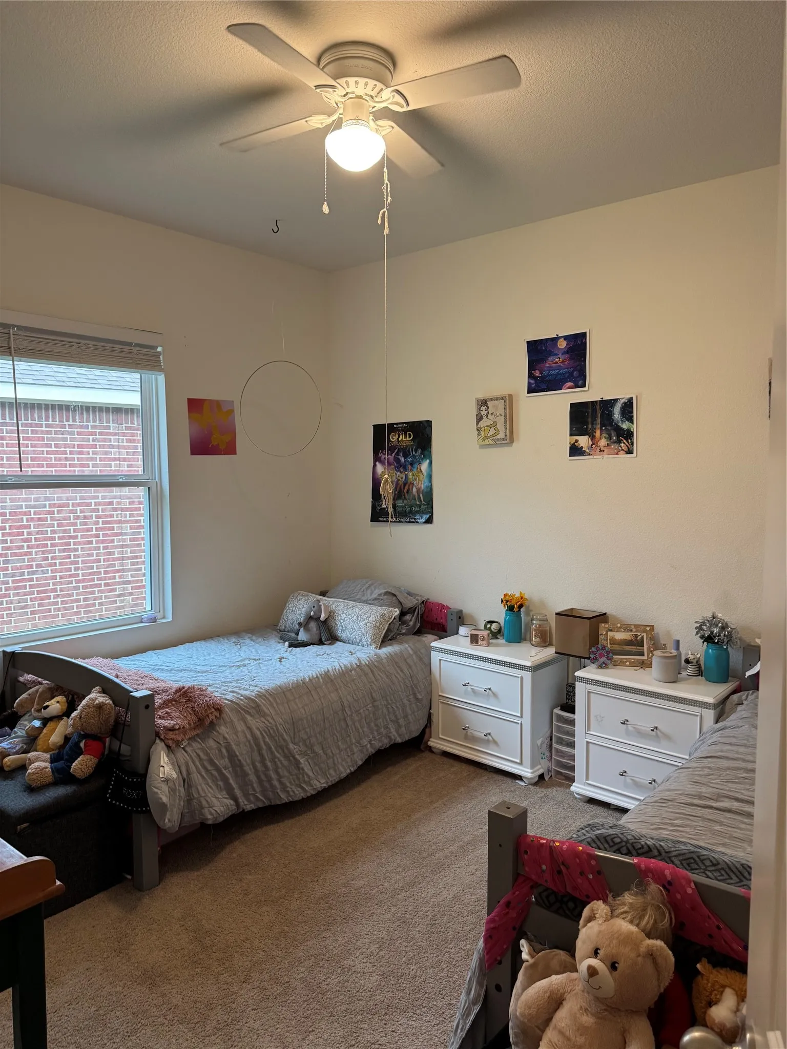 Carpeted room with a ceiling fan, two visible windows, and light-toned walls