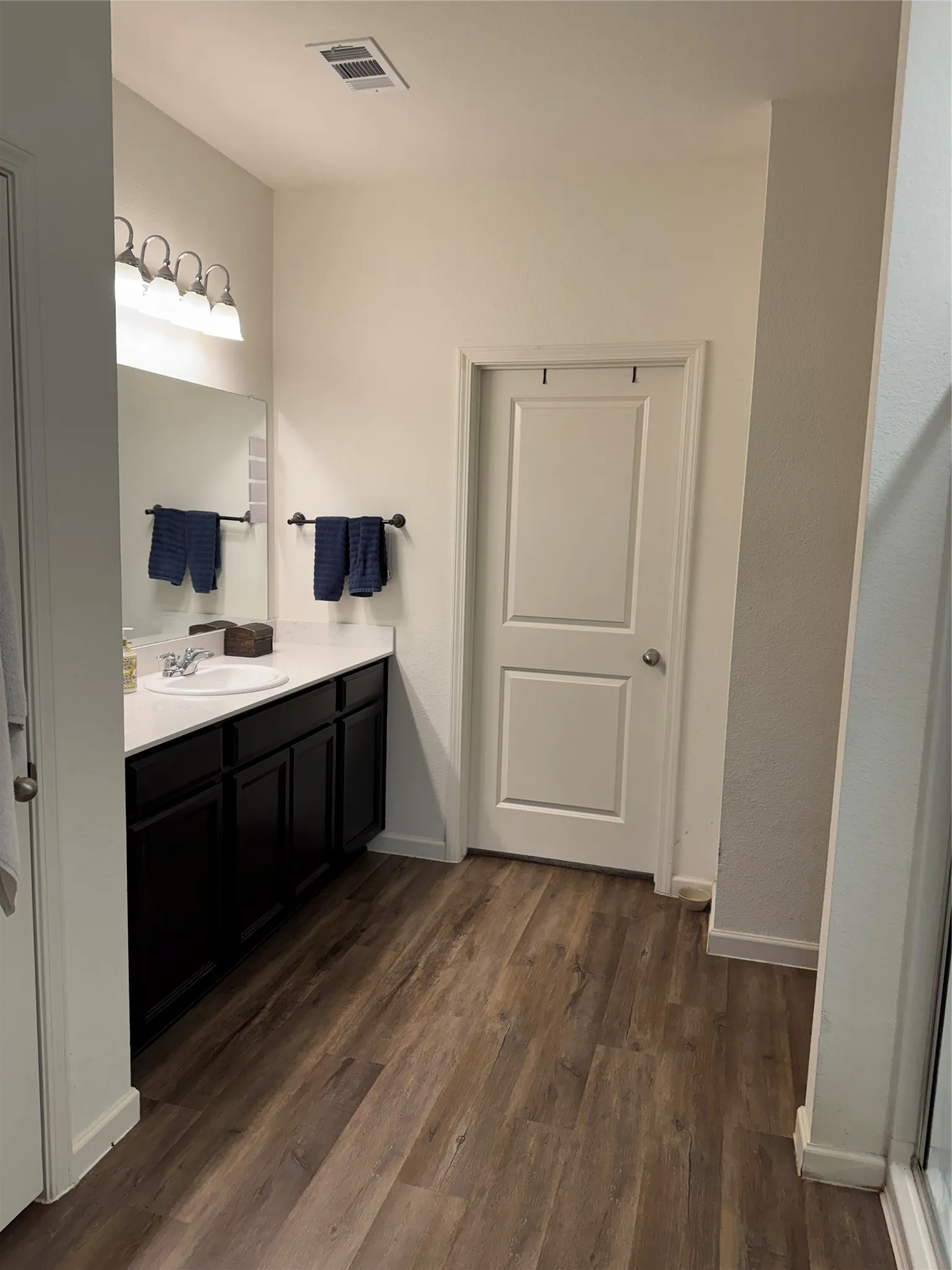 Bathroom featuring a dark wood-finish vanity with a white countertop and integrated sink
