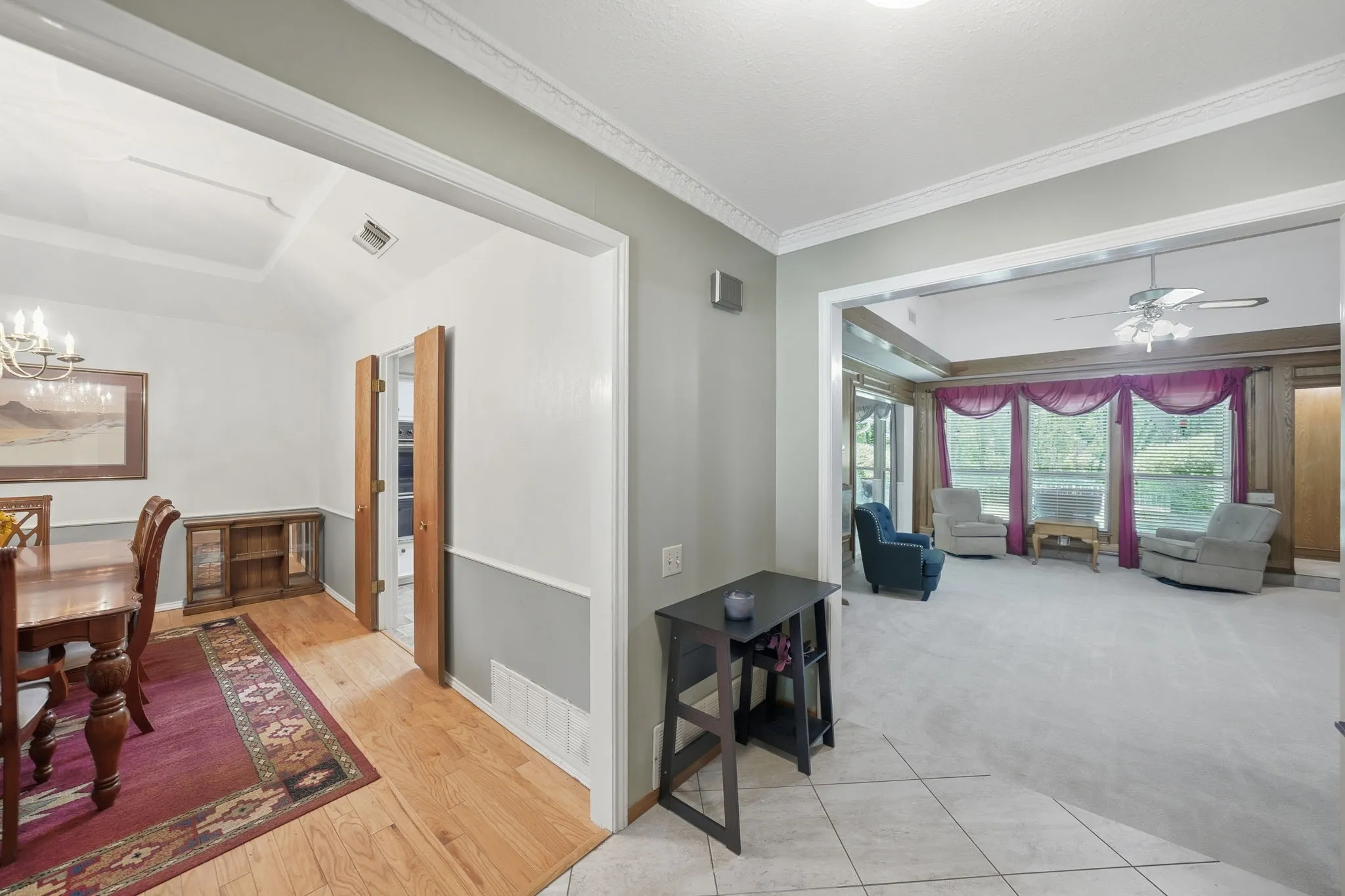 Open living spaces featuring light-colored carpet, a ceiling fan, and large windows