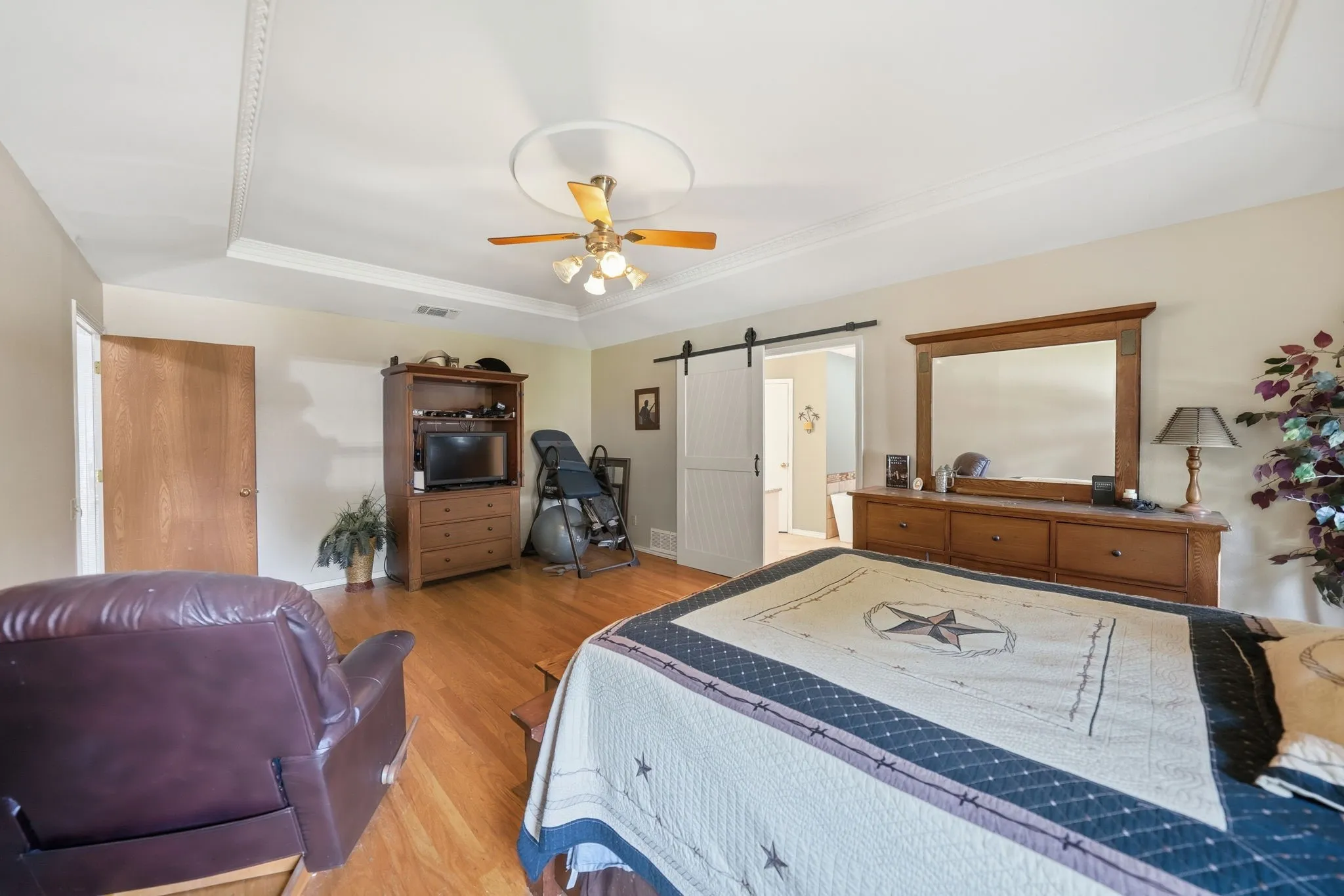 Hardwood-finish flooring featuring a tray ceiling and a ceiling fan