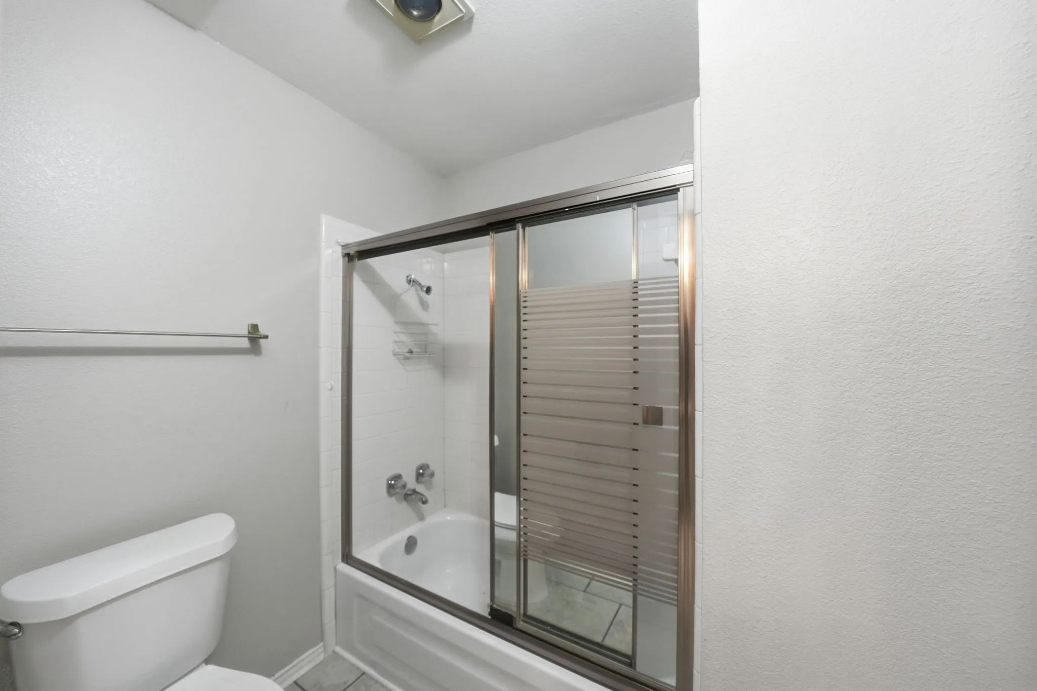 Bathtub with sliding glass enclosure featuring frosted privacy bands