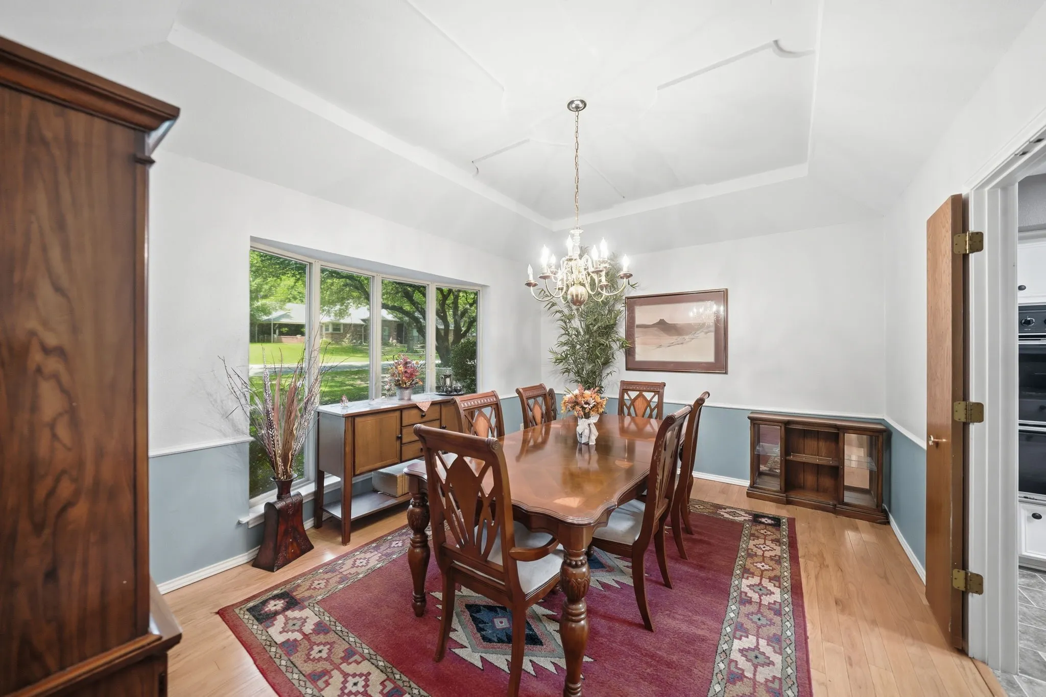 Dining area featuring a tray ceiling, chandelier lighting, and wood-finish flooring