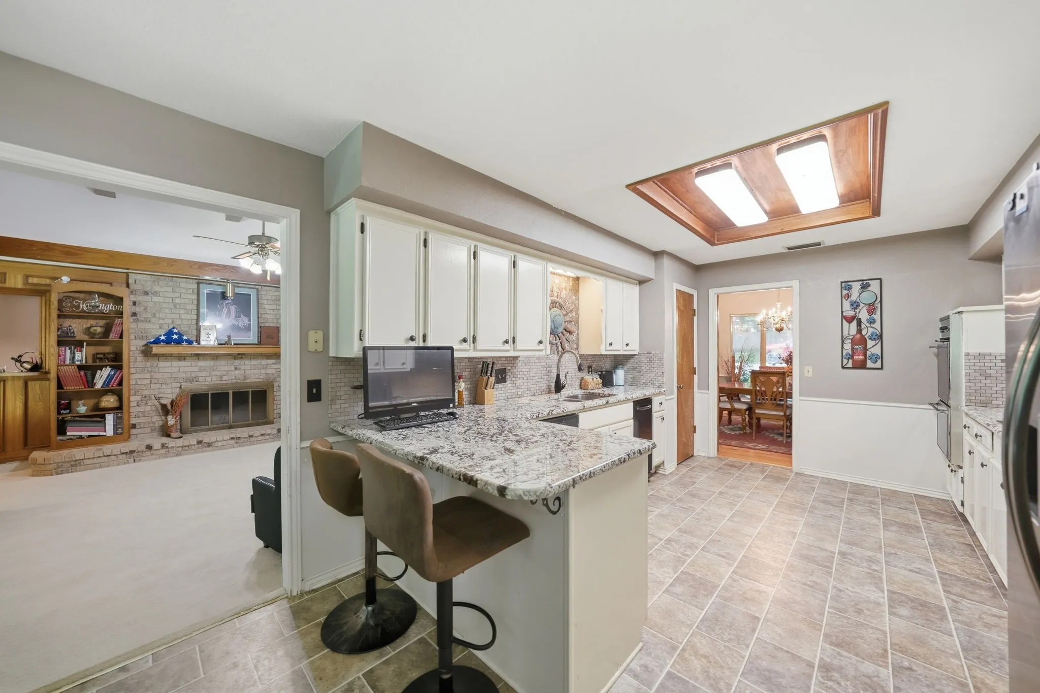 Kitchen featuring an island with stone-look countertop, integrated sink, and white cabinetry
