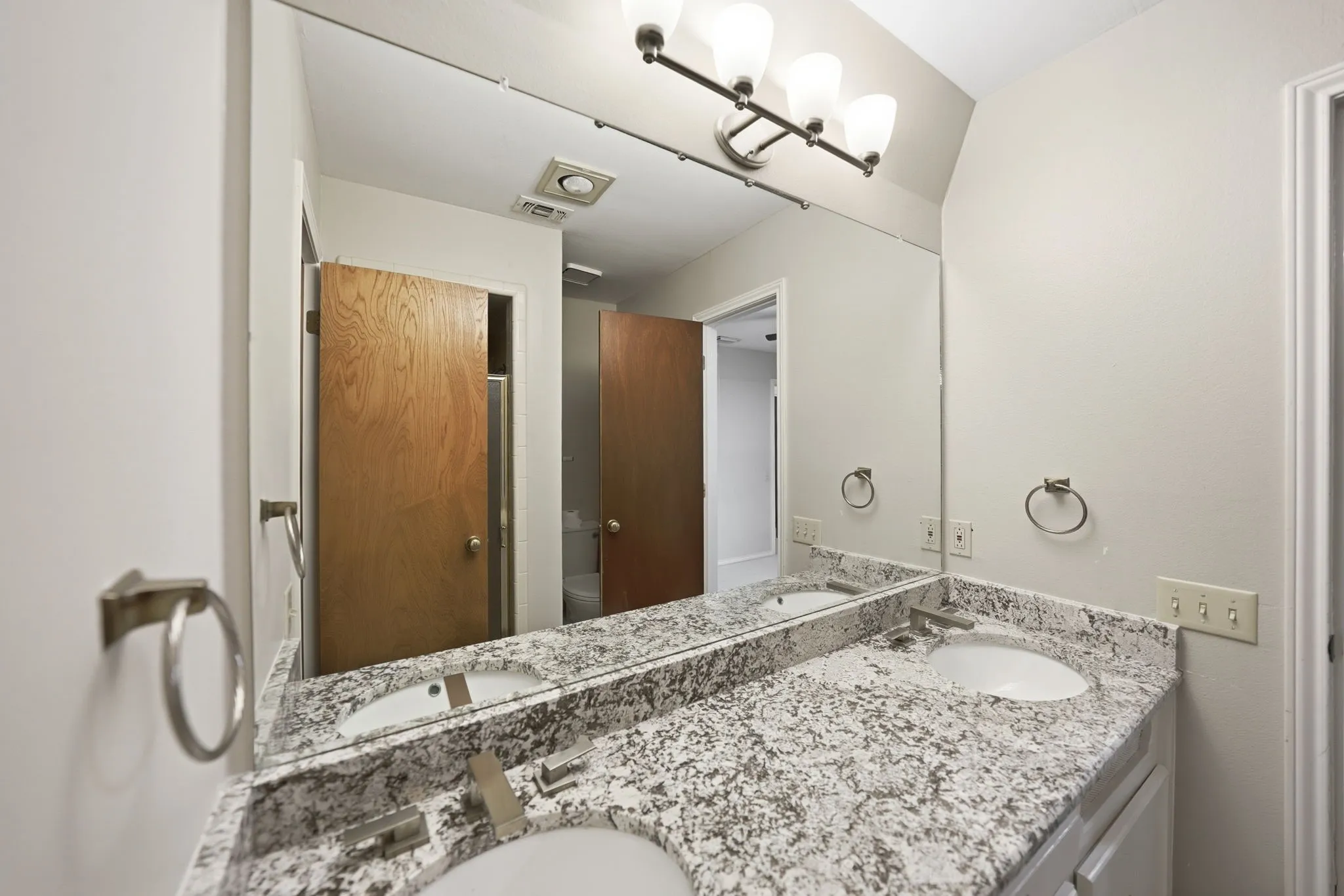 Bathroom vanity featuring dual undermount sinks, speckled stone-finish countertop, and brushed nickel fixtures