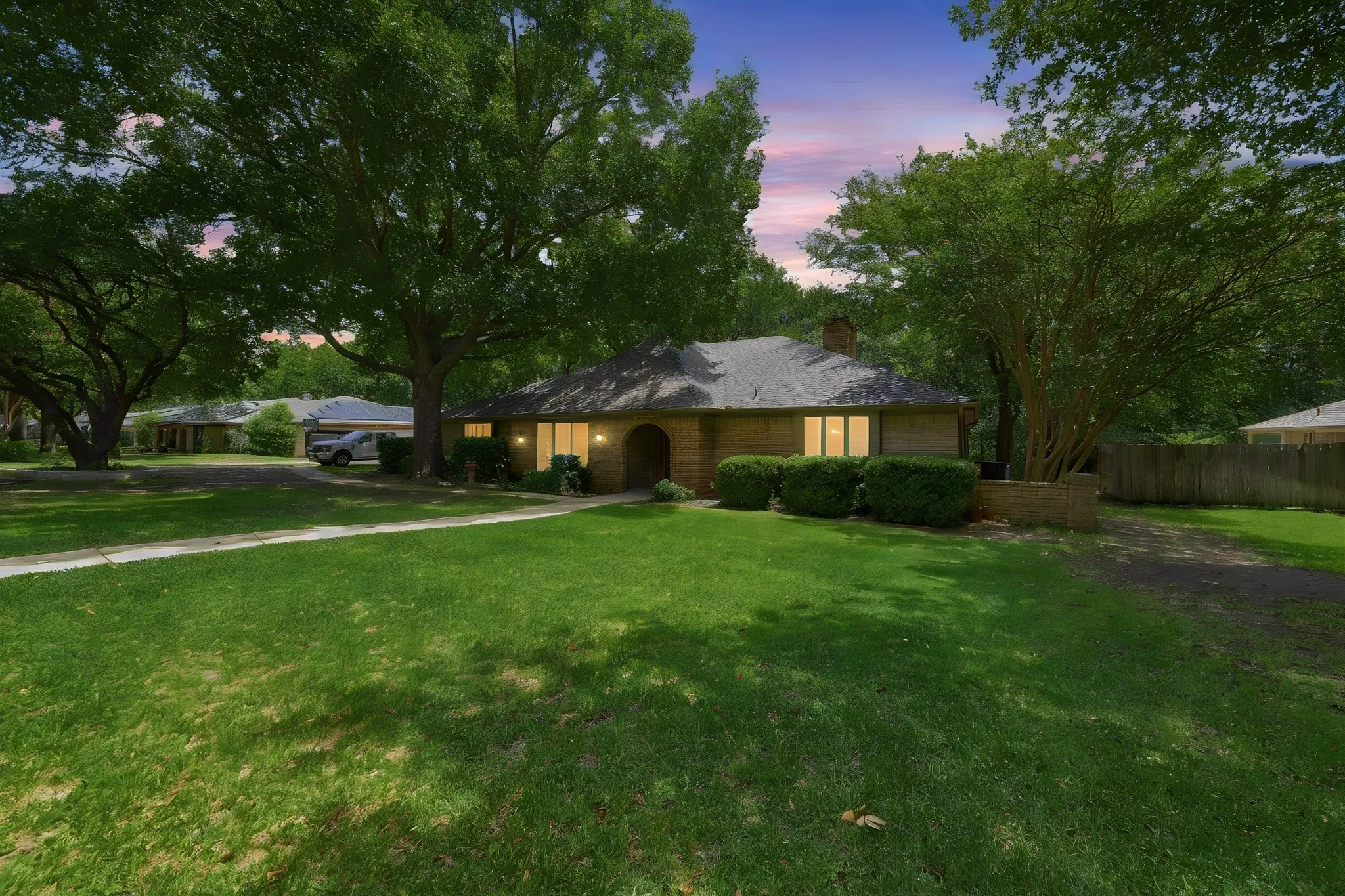 Brick exterior residence with a shingle roof, arched entry, and prominent front windows