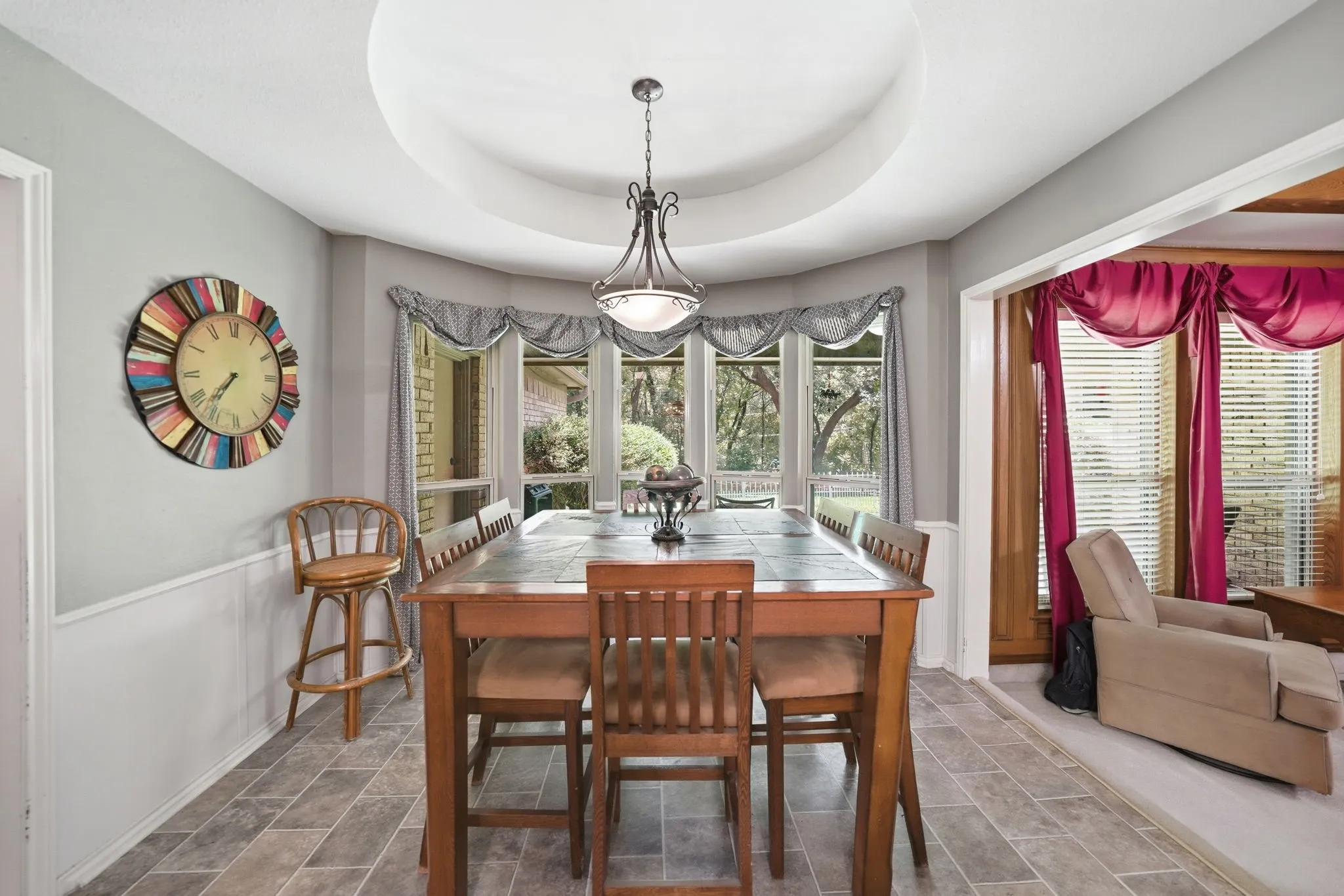 Dining area featuring a bay window, tray ceiling, and tile flooring