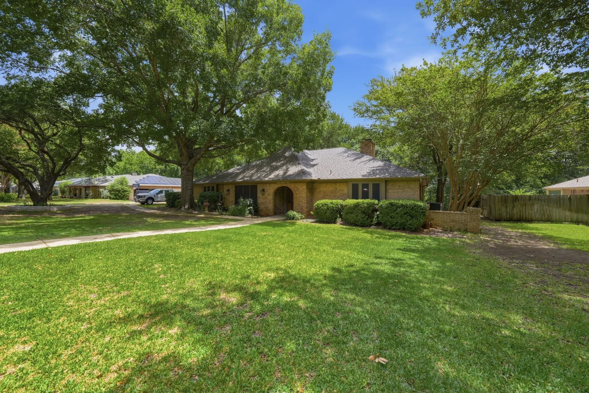 Brick exterior residence with a prominent arched entry and a light-colored shingle roof