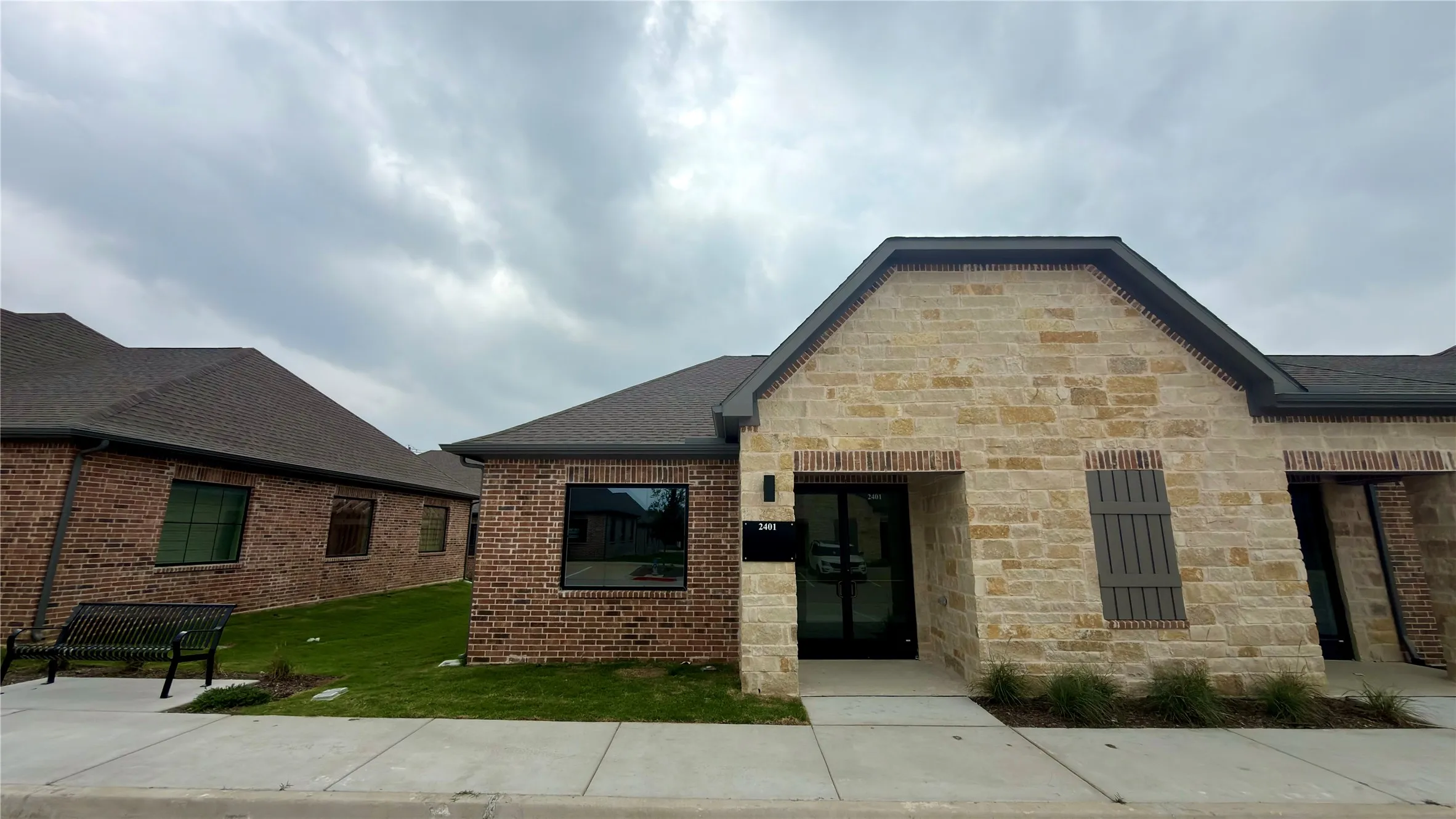 Stone and brick facade with dark trim, featuring a gabled entryway and decorative window shutters