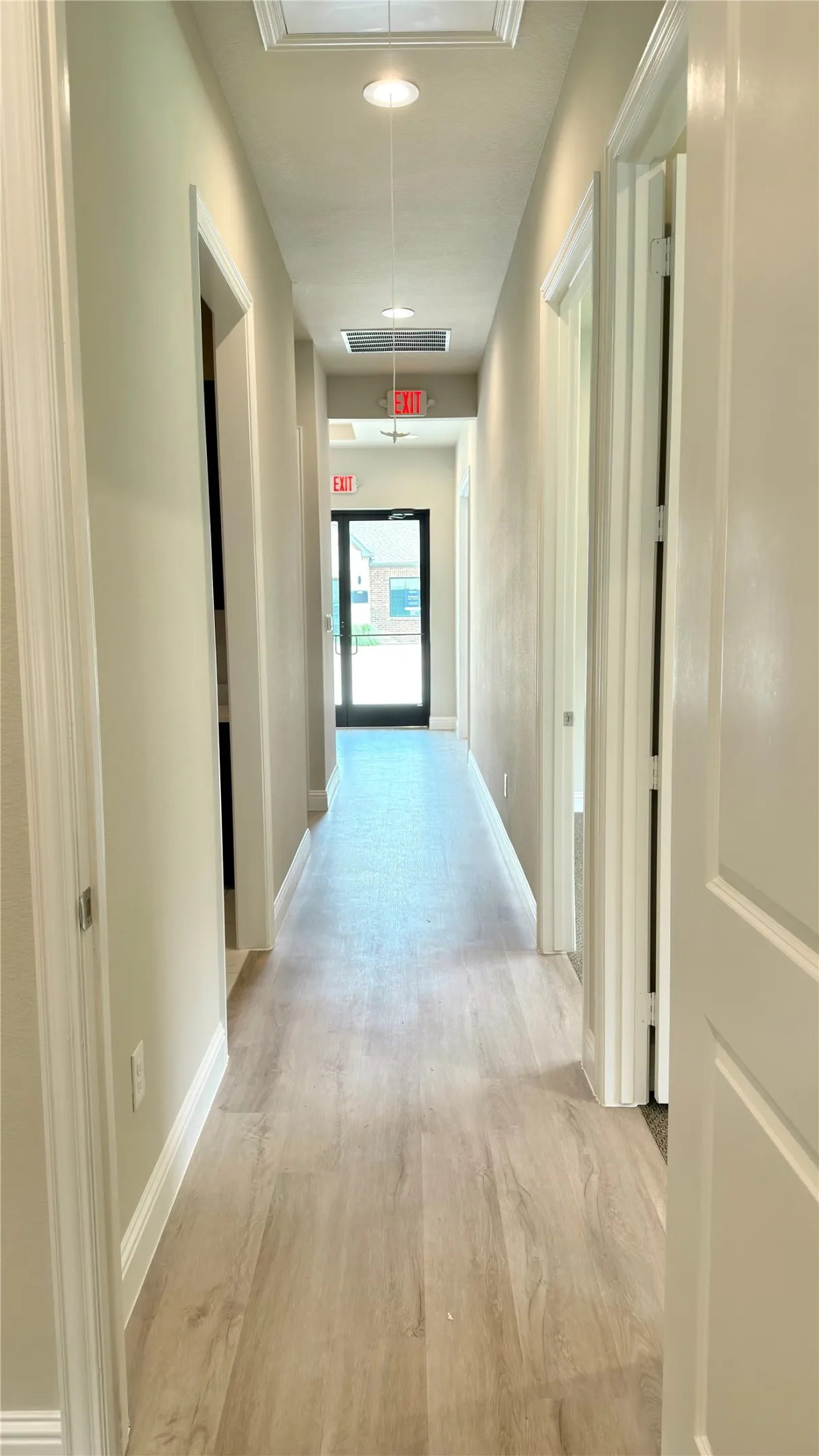 Hallway with wood-finish flooring, recessed lighting, white baseboards, and panel doors