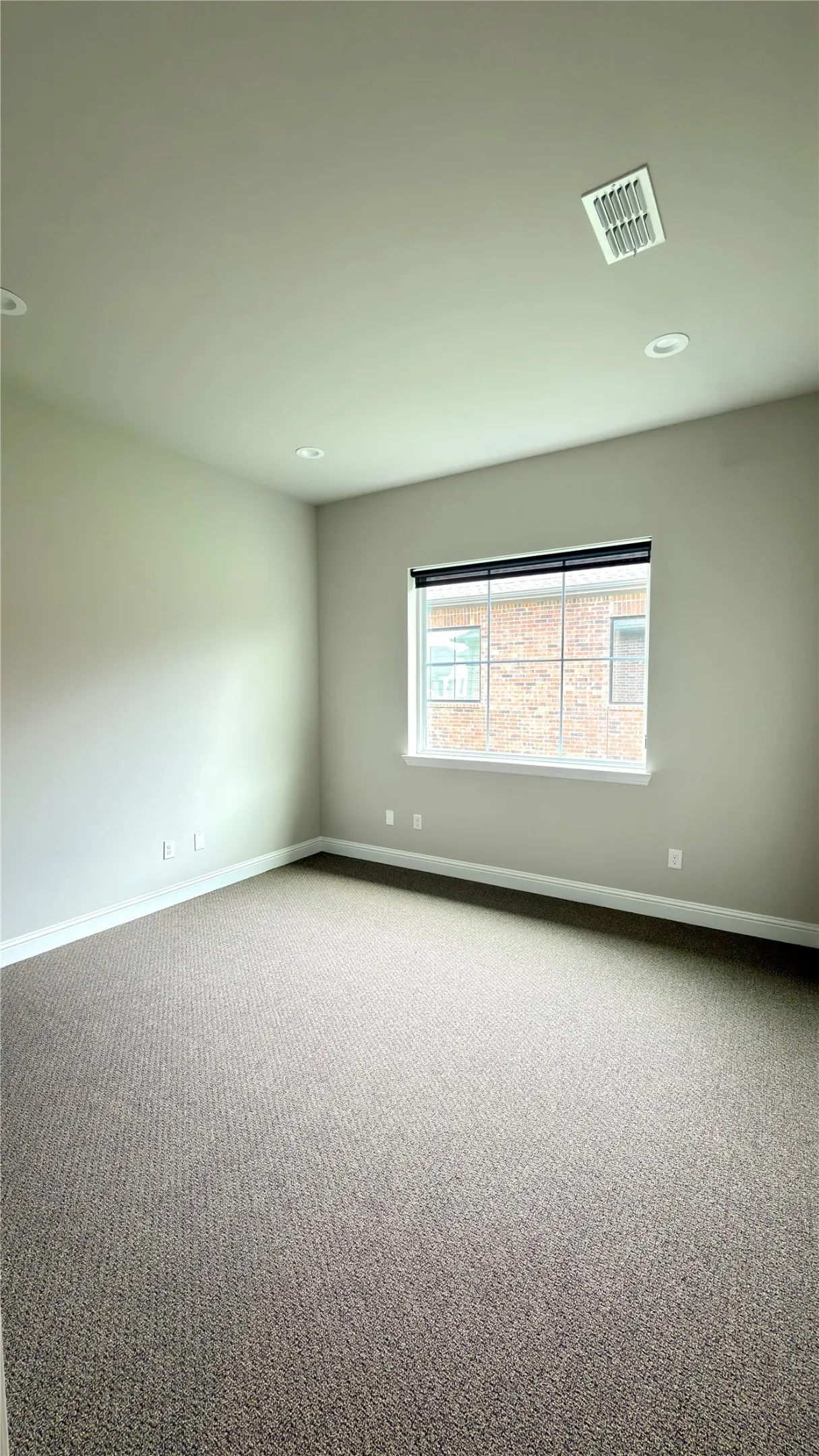 Carpeted room featuring a window with integrated blinds, recessed lighting, and a ceiling-mounted air vent