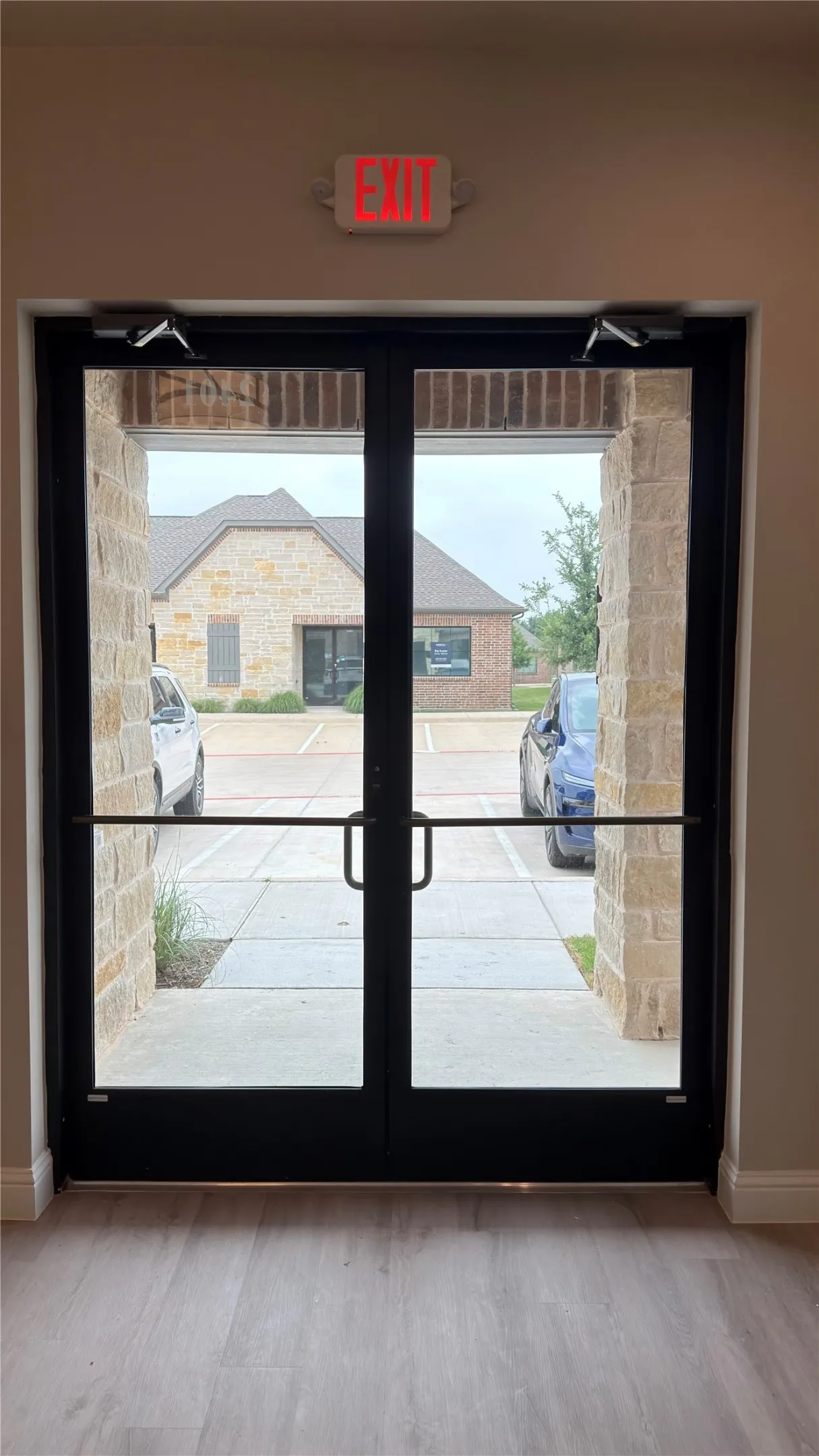 Double glass doors with black framing, featuring panic bars and overhead door closers
