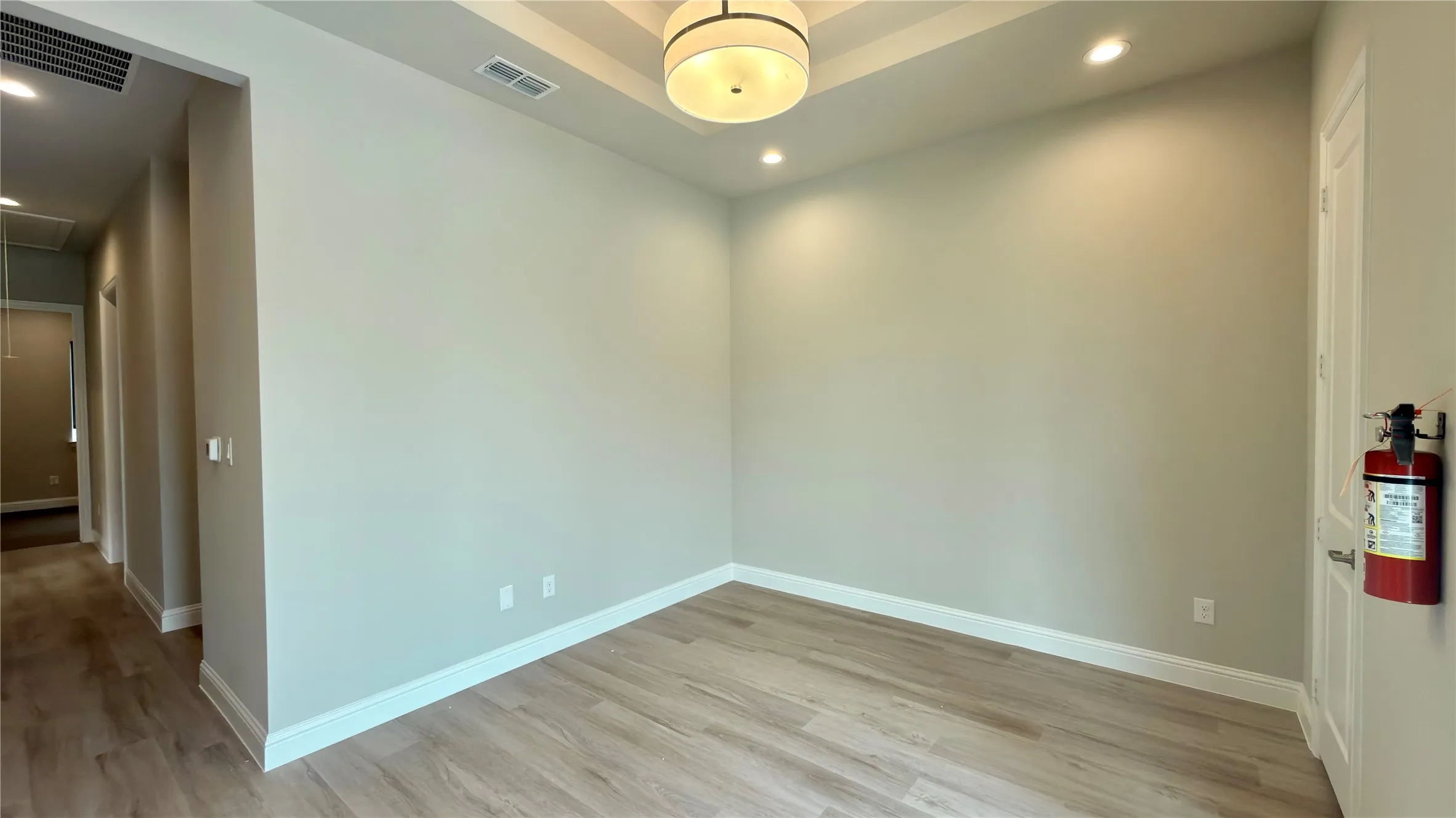 Spacious room featuring wood-finish flooring, a coffered ceiling with a central drum pendant light, and recessed lighting