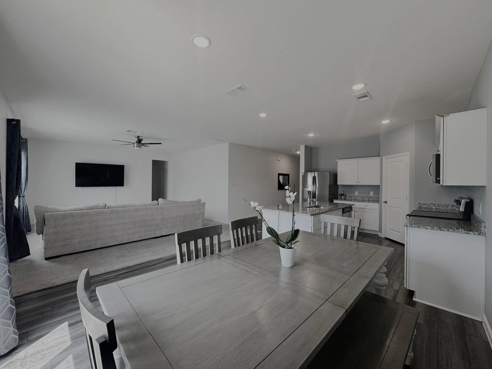 Open-concept living space featuring wood-finish flooring, recessed lighting, a ceiling fan, white cabinetry, and stainless steel appliances