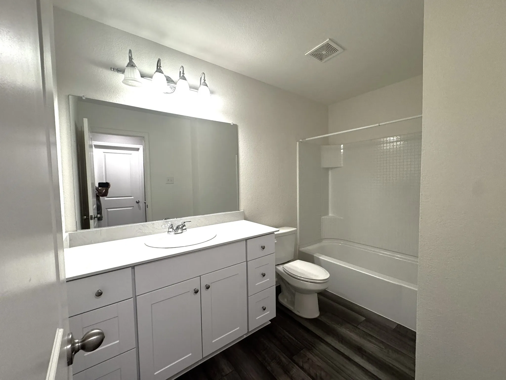 Bathroom featuring a white vanity with an integrated sink, polished chrome faucet, and a large wall-mounted mirror