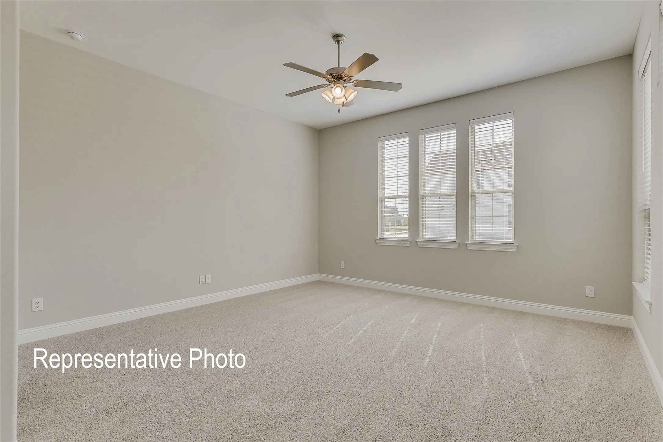 Spacious room featuring neutral carpeting, light-toned wall paint, and white baseboards