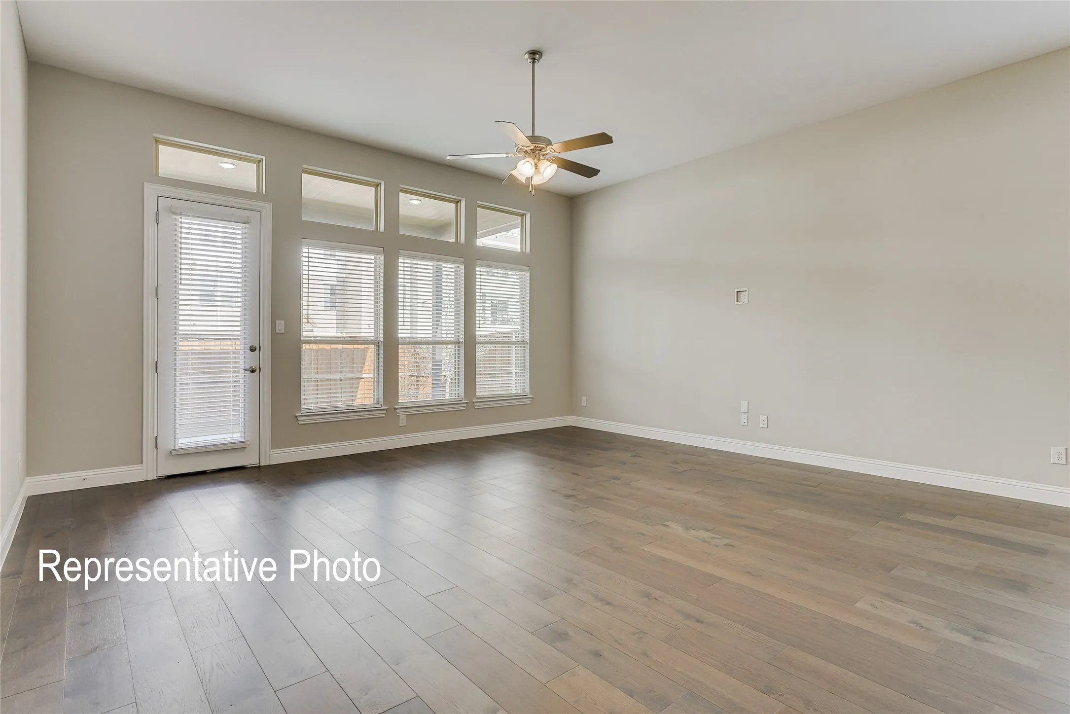 Spacious interior featuring wood-finish flooring, a contemporary ceiling fan, and high ceilings