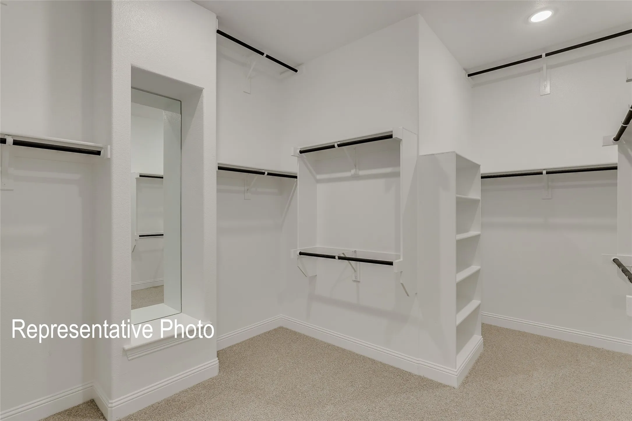 Spacious walk-in closet featuring built-in shelving, multiple hanging rods, recessed lighting, and a full-length mirror