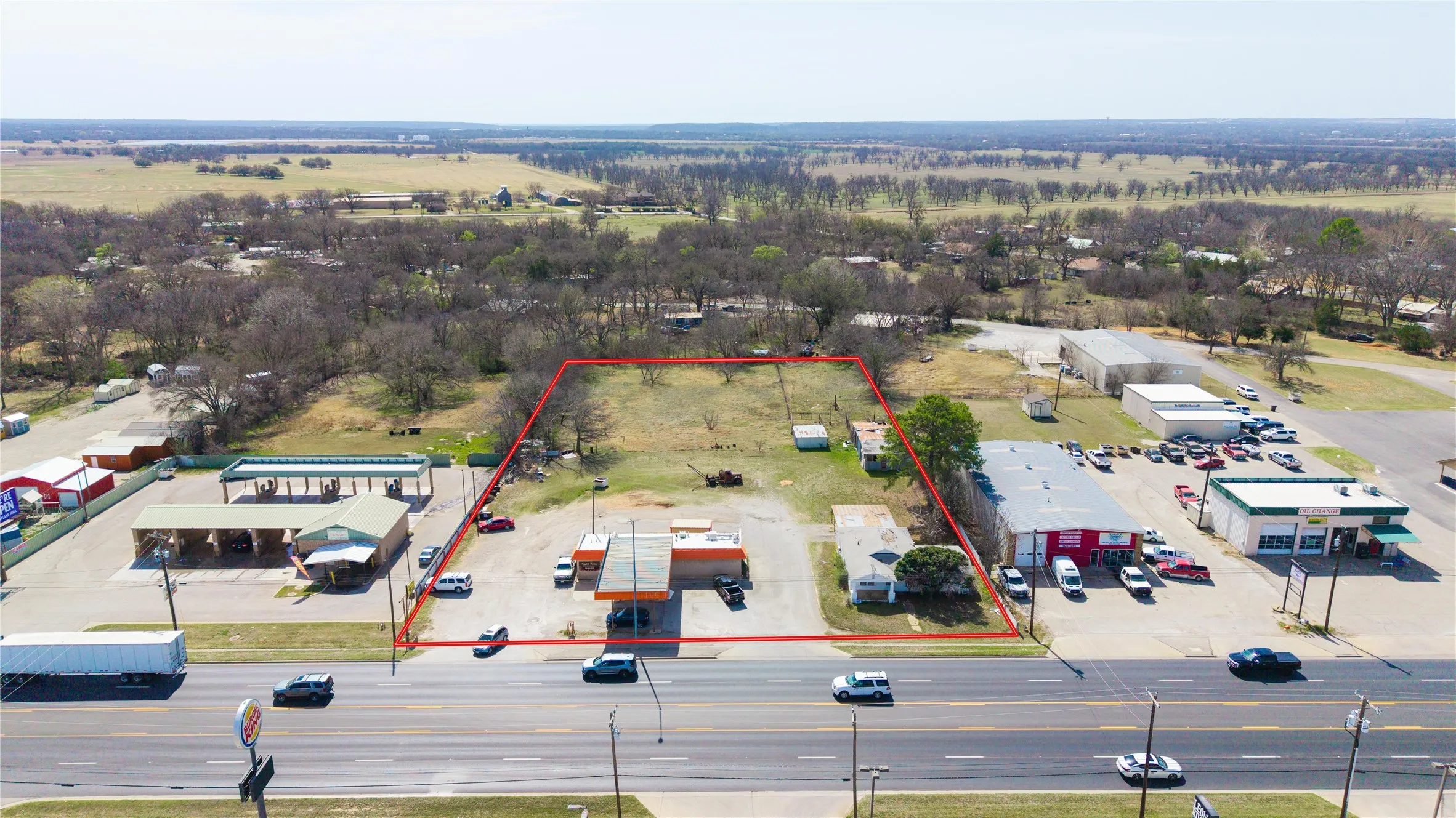 Expansive commercial lot with significant road frontage, featuring two existing structures and ample undeveloped land