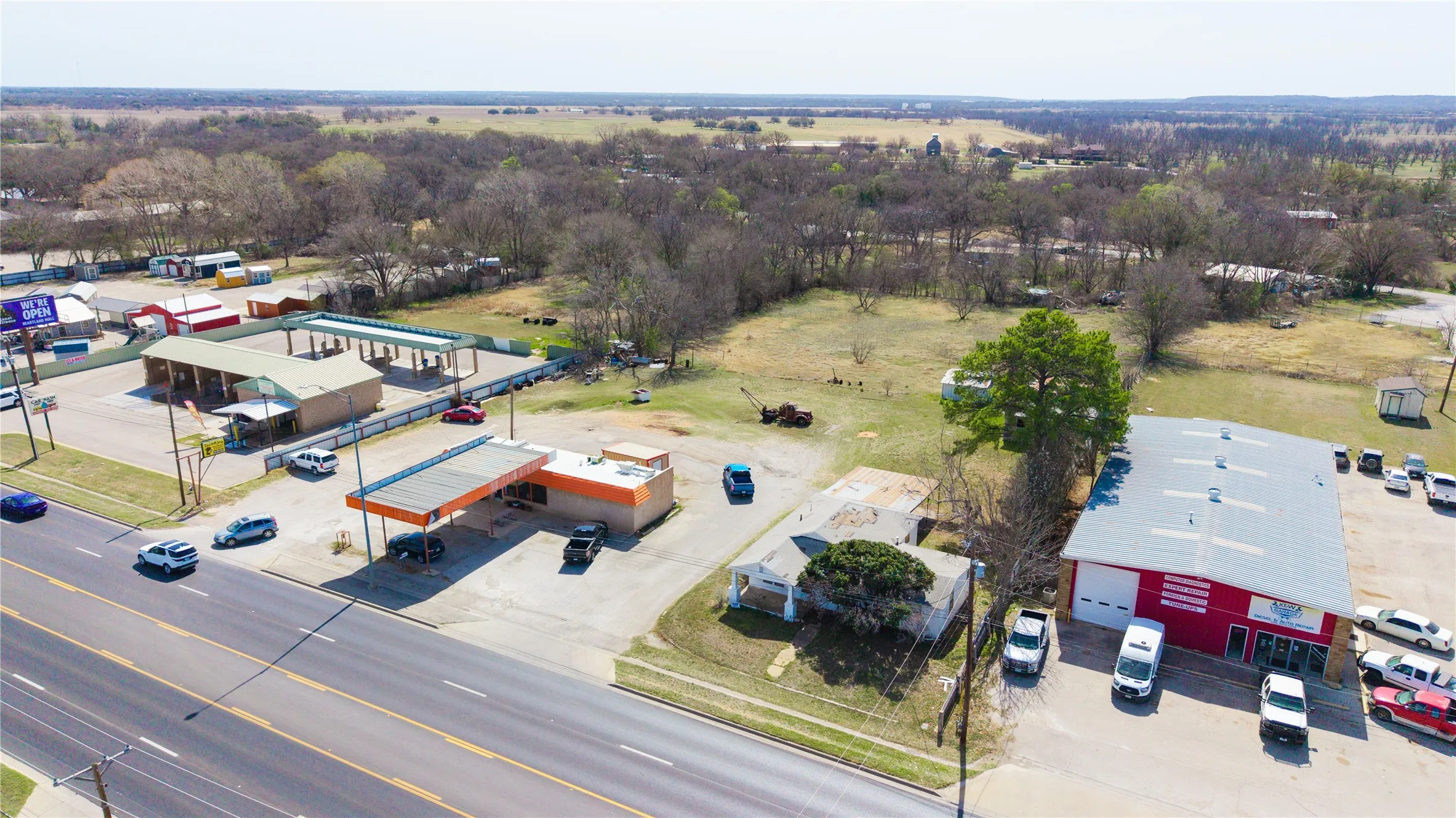 Commercial property featuring multiple structures, extensive paved areas, and direct road frontage