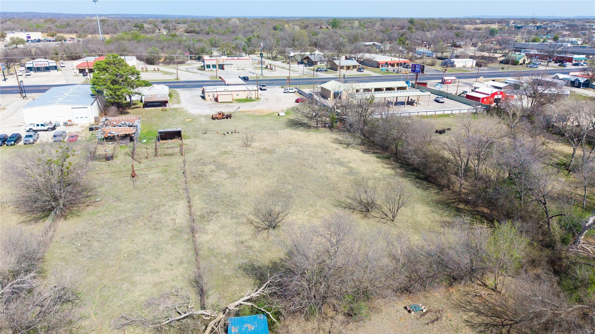Expansive land parcel featuring open fields and mature trees, bordered by a fence line
