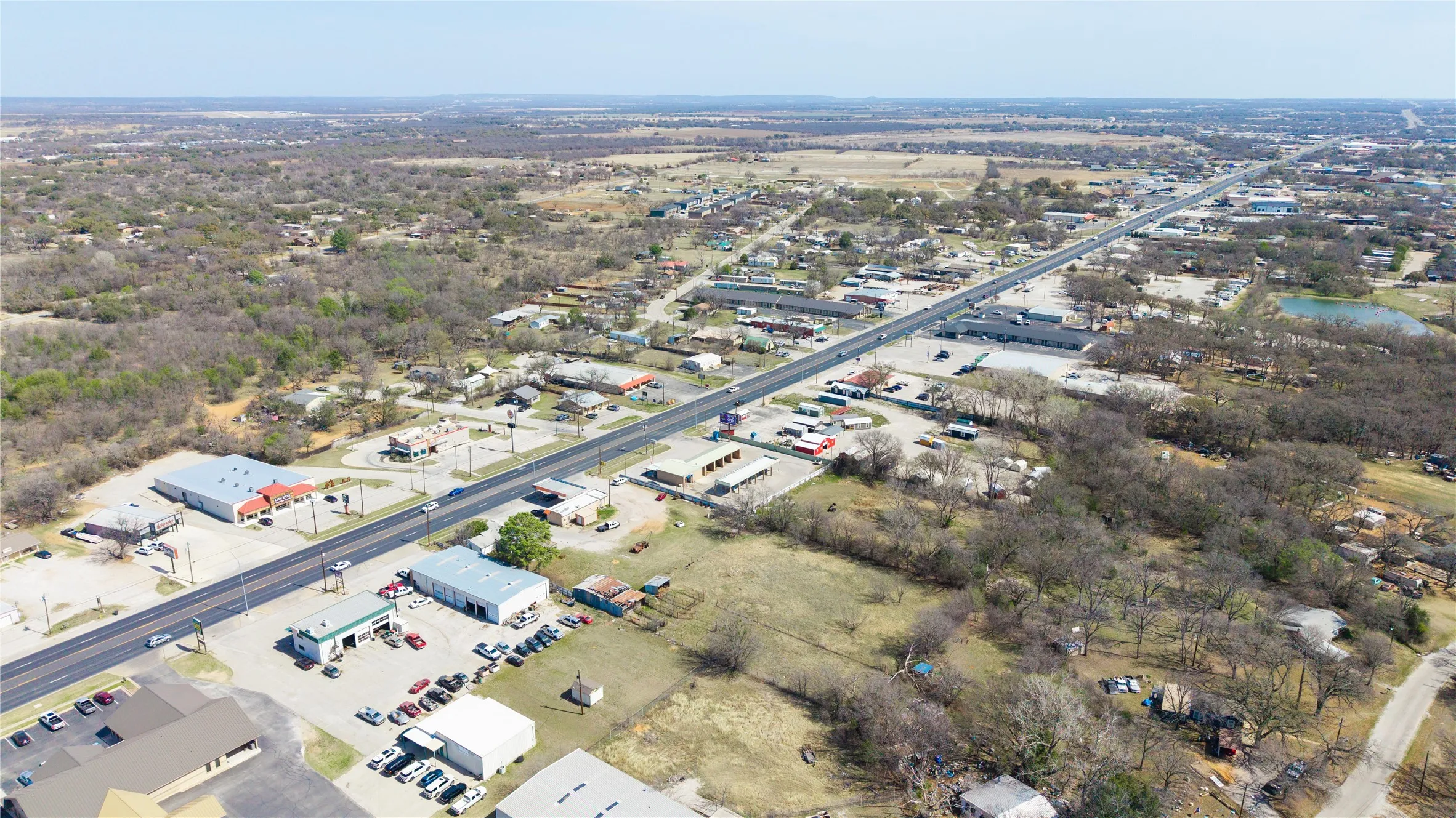 Expansive aerial perspective showcasing a commercial corridor with multiple buildings and paved parking areas