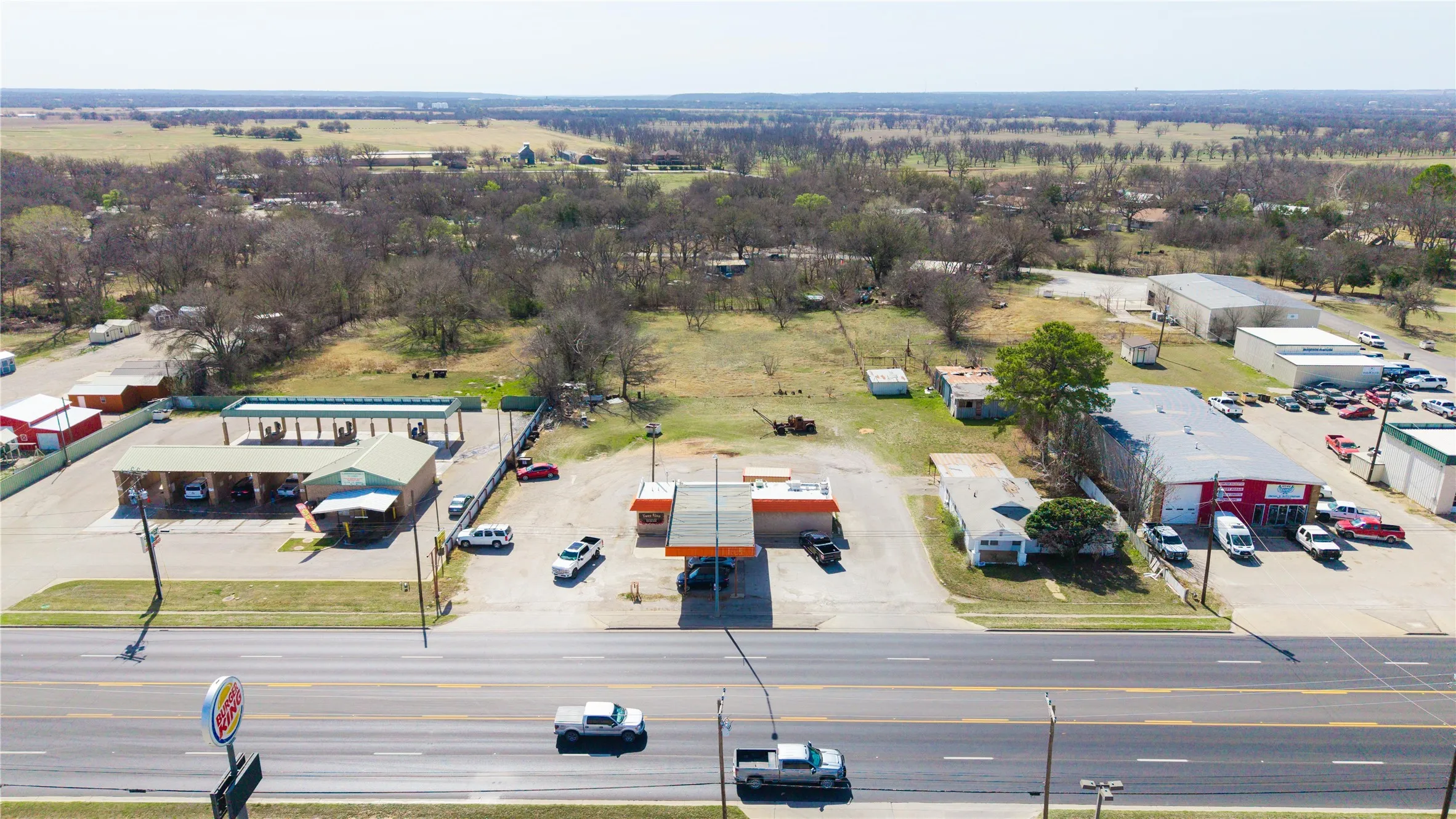 Roadside commercial property featuring a car wash facility with multiple bays, a gas station canopy, and an adjacent commercial building
