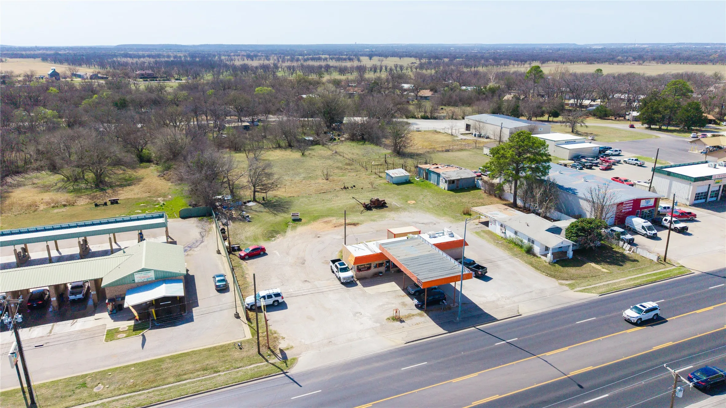 Commercial property featuring a gas station canopy, adjacent buildings, and a multi-bay car wash structure