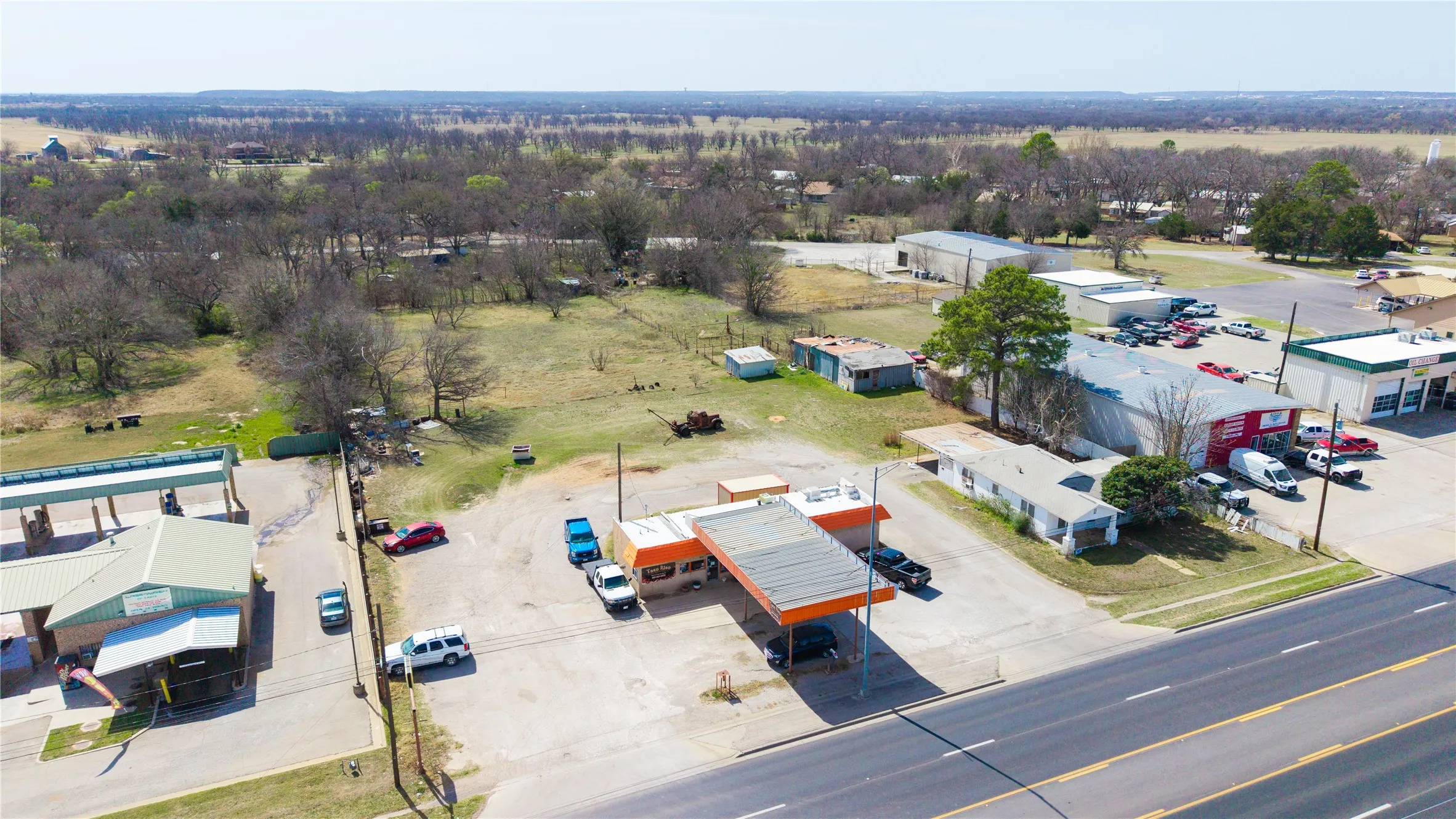 Commercial property featuring multiple structures, extensive paved parking, and direct frontage on a paved road