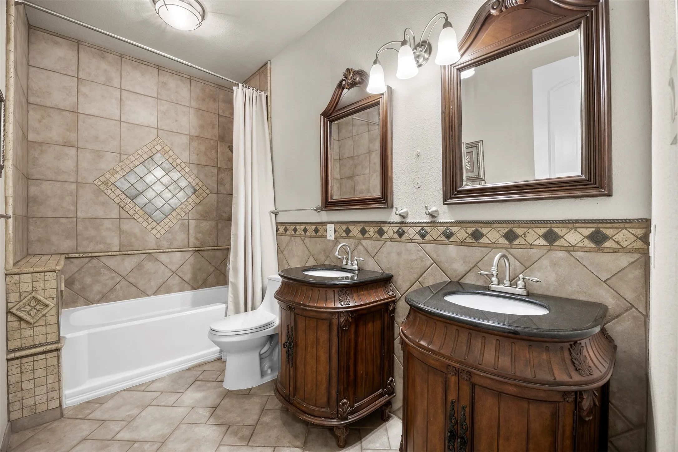 Beautifully finished full bath situated between the secondary bedrooms with dual vanities, custom cabinetry, & detailed tilework.
