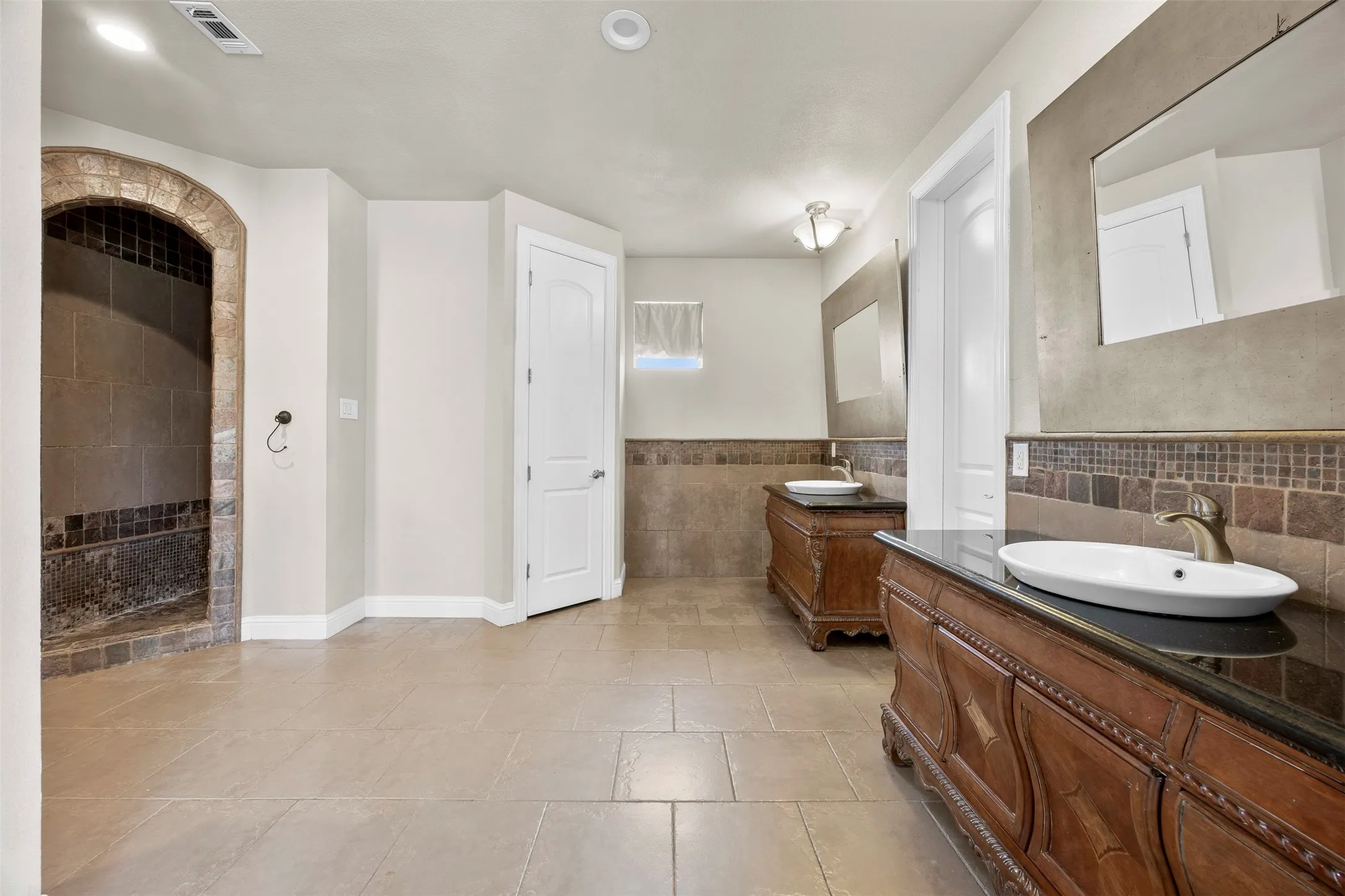 Expansive primary bath with dual custom vanities, oversized walk-in shower, abundant storage, & elegant custom finishes throughout.