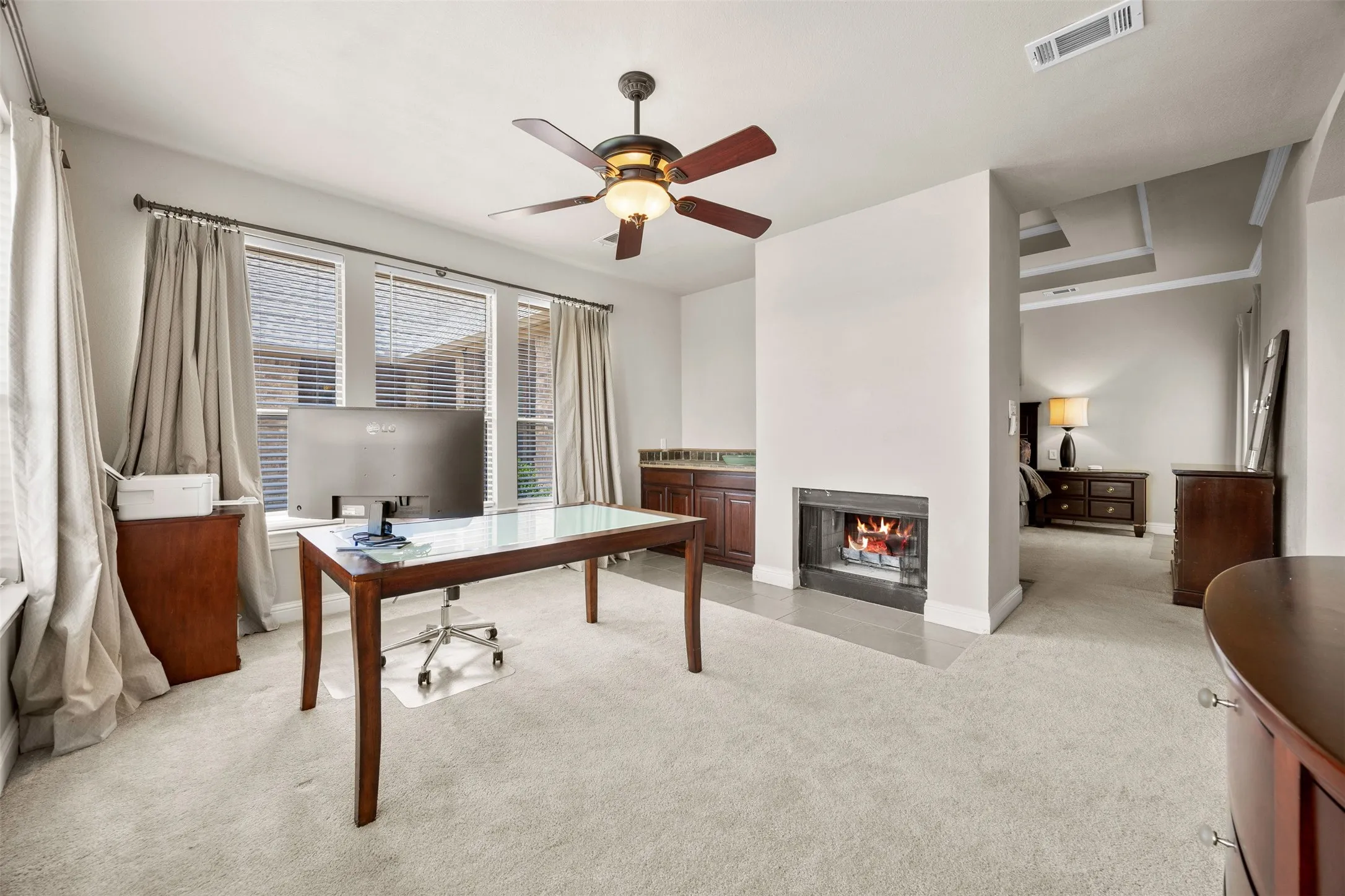 Private sitting area, reading nook, nursery or office space located just off the primary suite featuring backyard views, a double-sided fireplace shared with the bedroom, & a built-in wet bar for added comfort and convenience