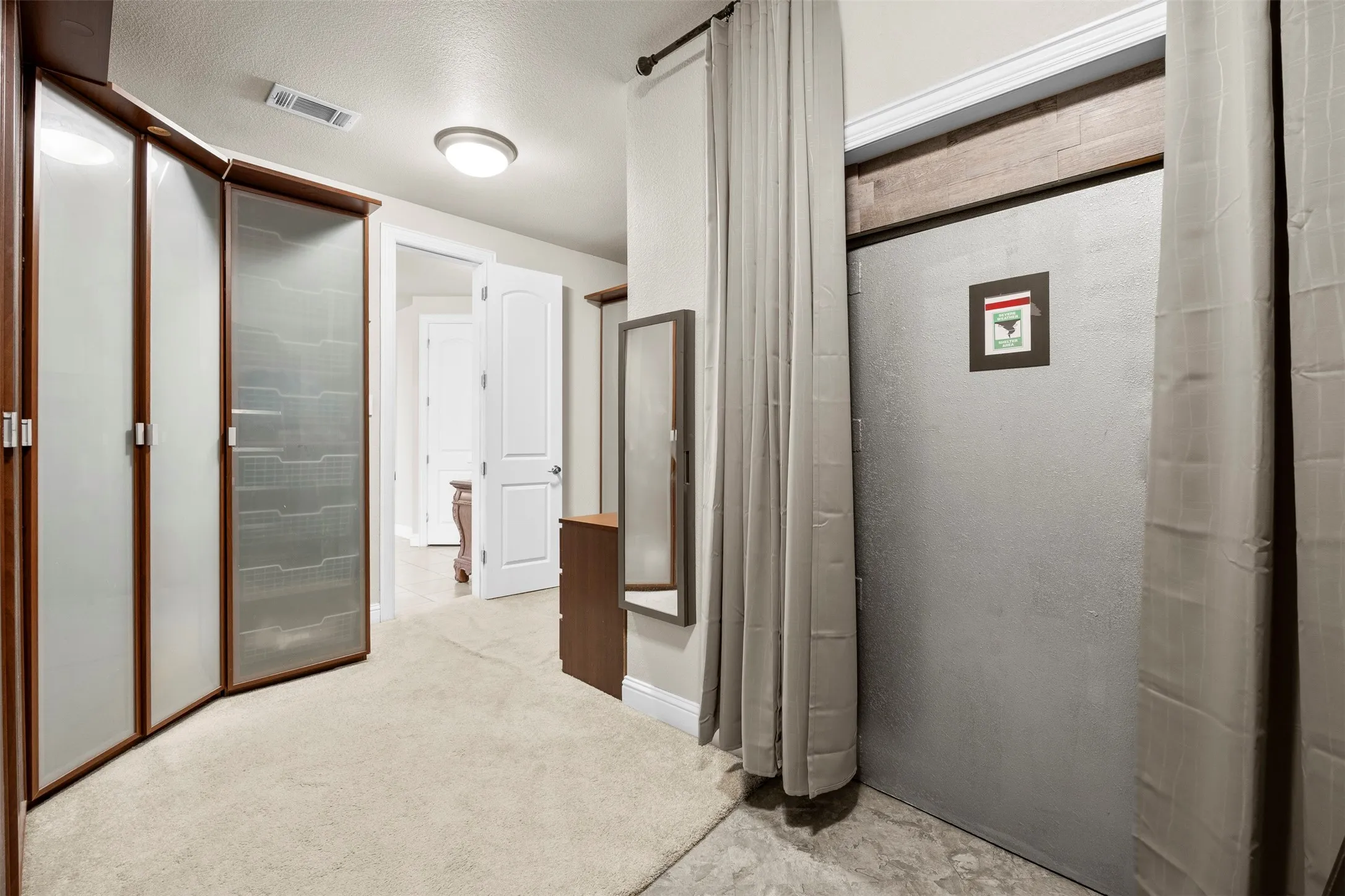 Custom primary closet featuring built-in storage system, abundant organization space, & a discreet 8x6 tornado shelter complete with panic button for added peace of mind.