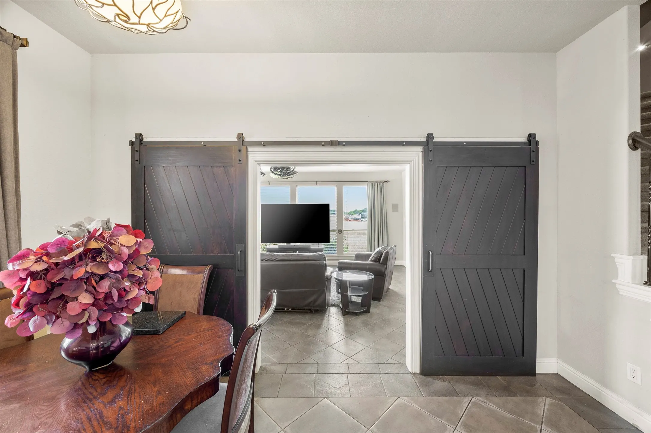 View from the kitchen into the eat-in breakfast area and flex space/man cave, featuring custom sliding barn doors and an open-concept layout.