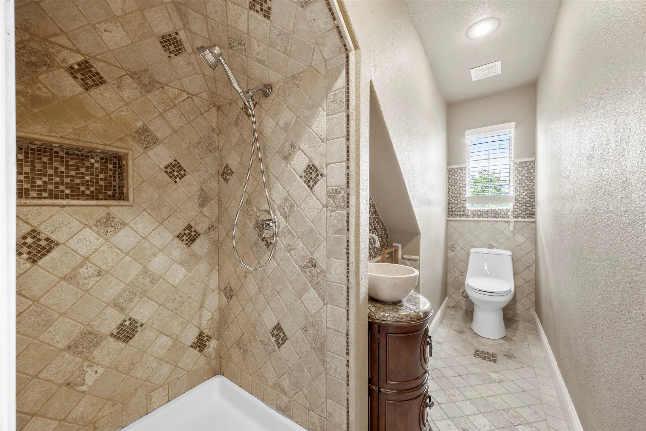 Upstairs full bathroom with custom tile shower and decorative vanity.