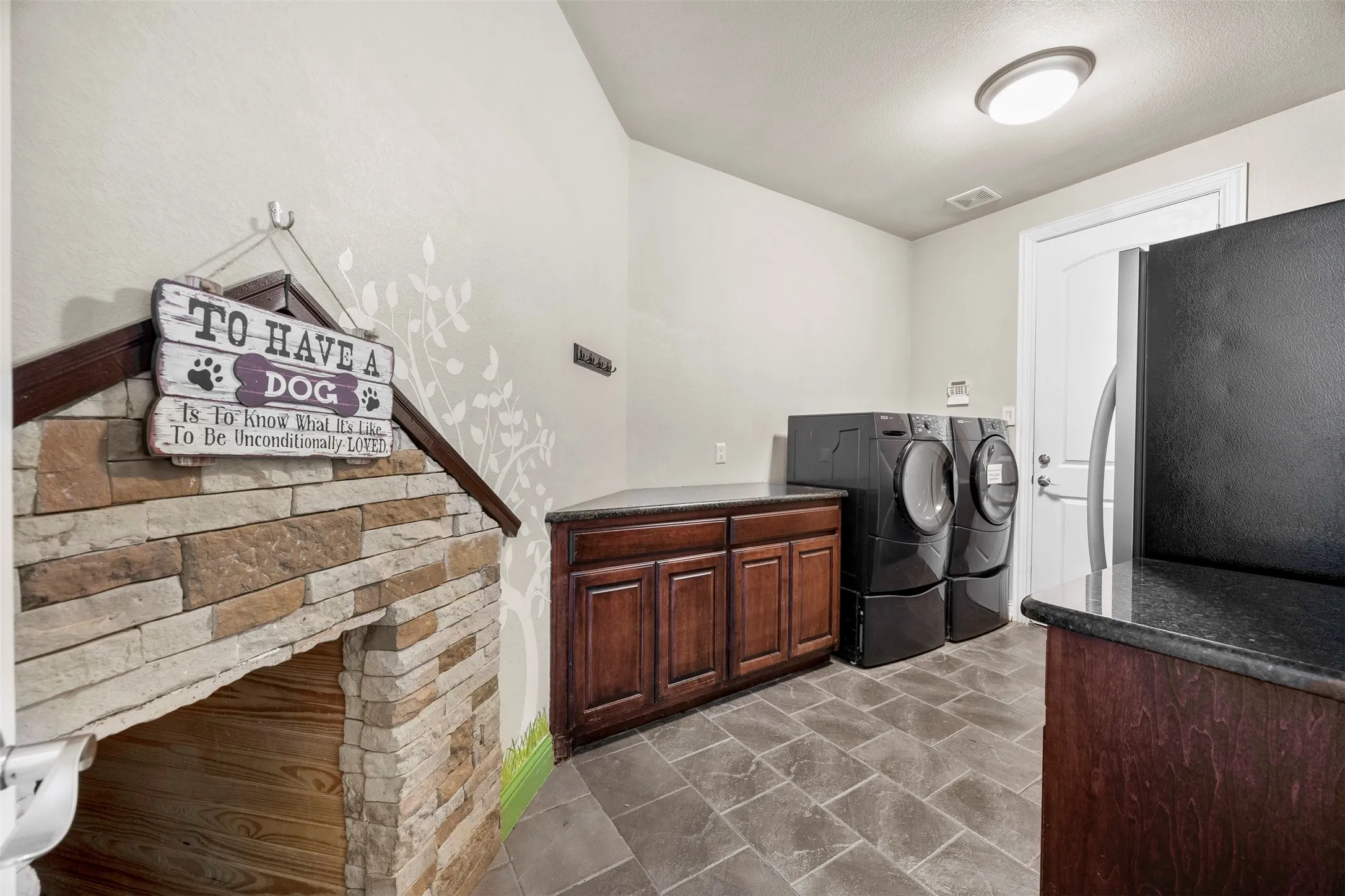 Oversized utility room with abundant cabinet storage, space for an additional refrigerator or freezer, direct access to the 3-car garage, & a built-in 5x3 dog house.