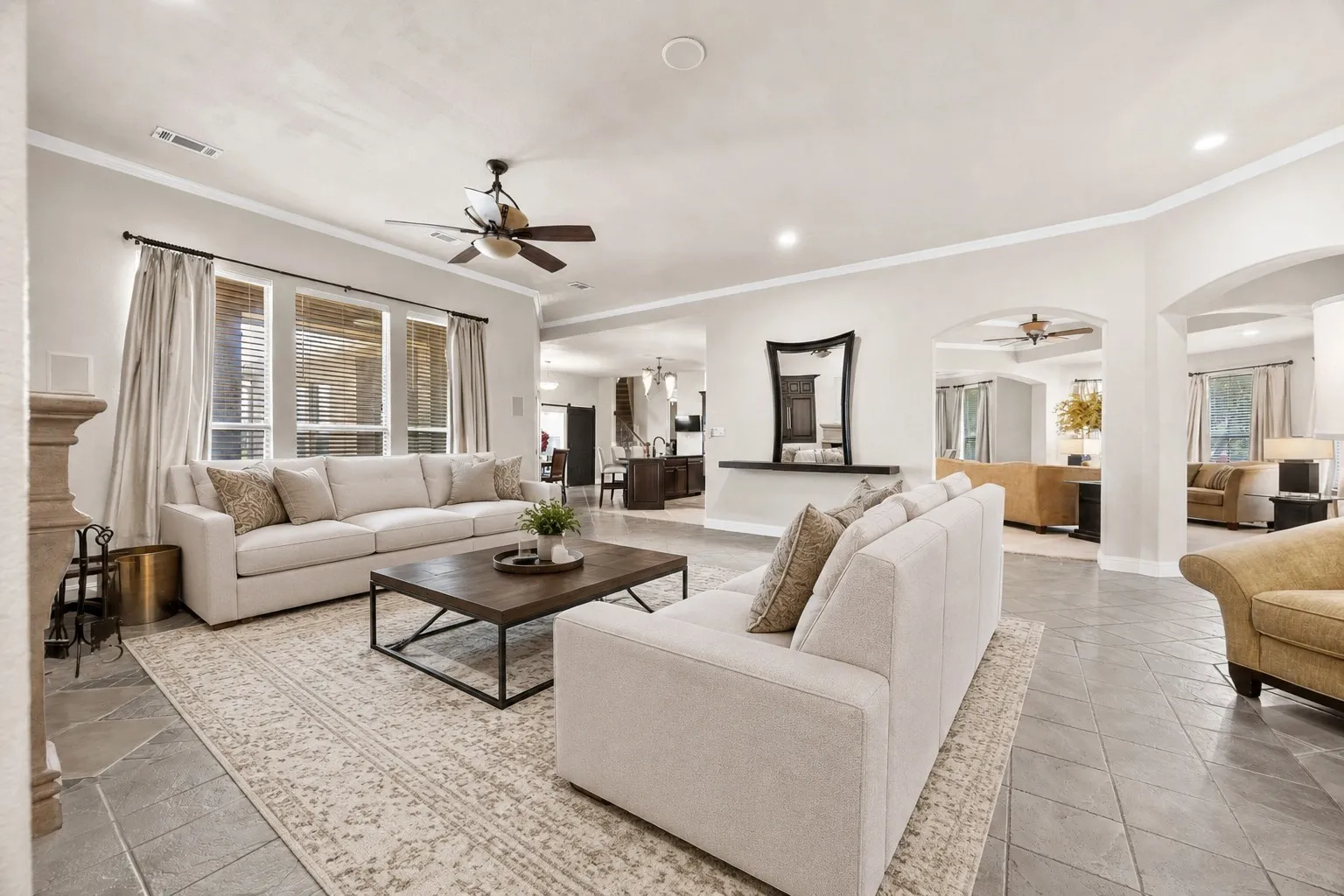 Open-concept living room with fireplace, soaring ceilings, and spacious seating area perfect for entertaining. (virtually staged)