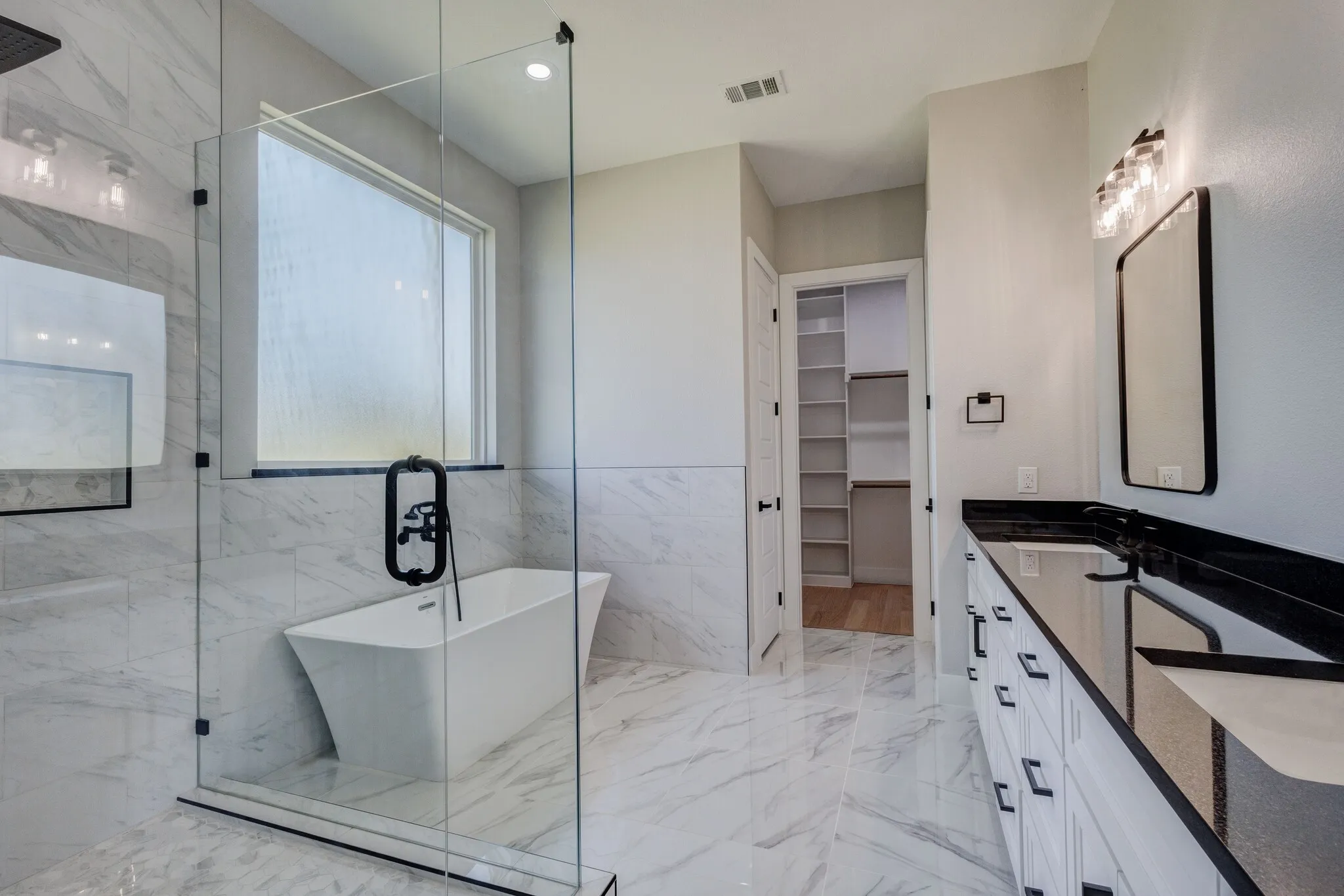 Freestanding soaking tub within a glass-enclosed shower featuring a rainfall showerhead