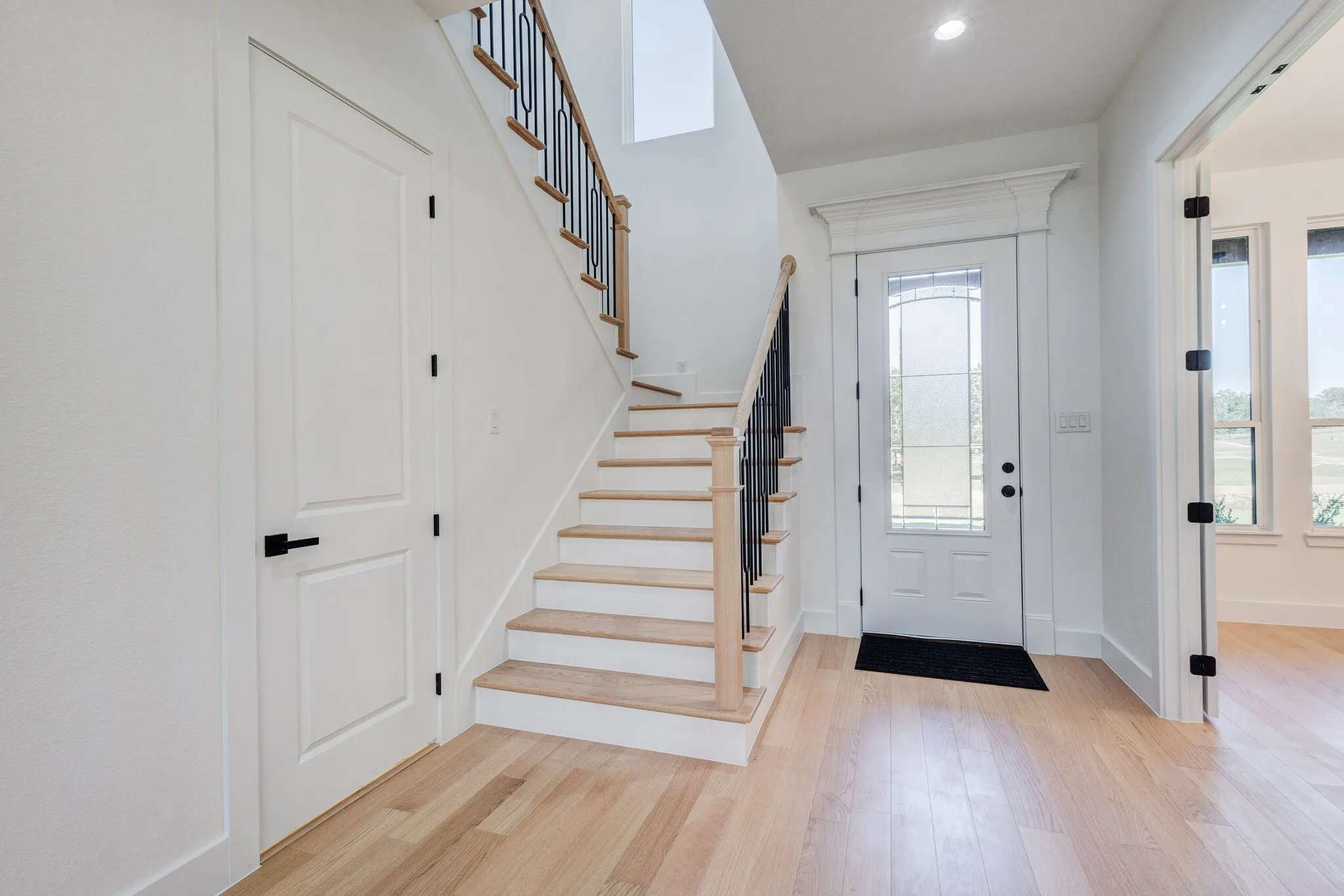 Light wood-finish flooring extending through the entry and into adjacent spaces