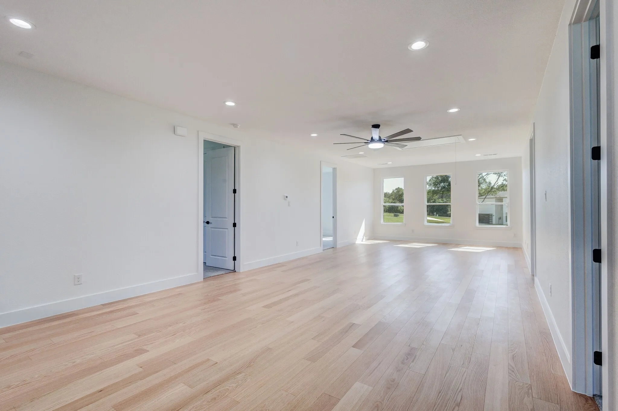 Spacious room featuring wood-finish flooring, recessed lighting, and a contemporary ceiling fan
