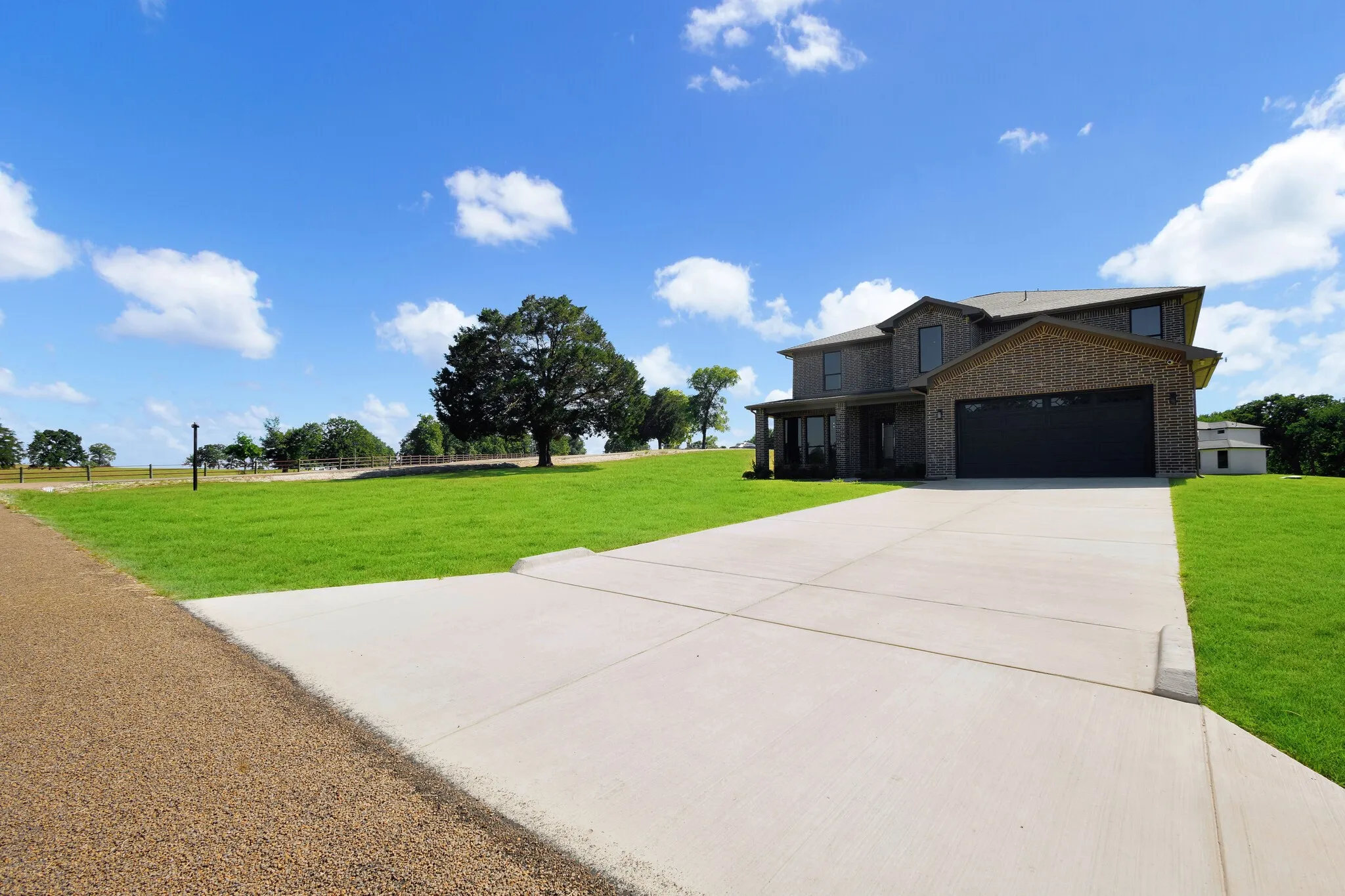 Two-story brick exterior with a prominent concrete driveway and attached garage