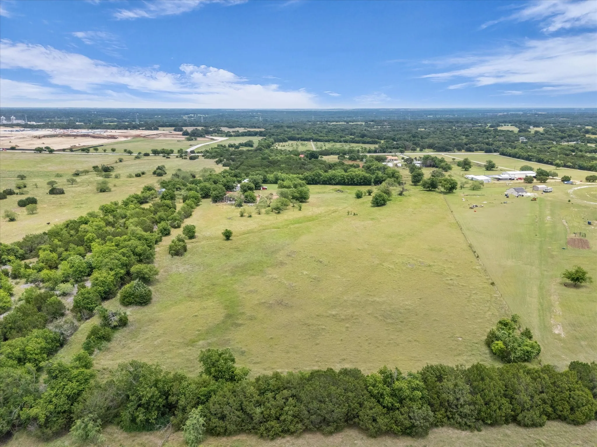 Expansive acreage featuring established tree lines, open pastures, and distant residential structures