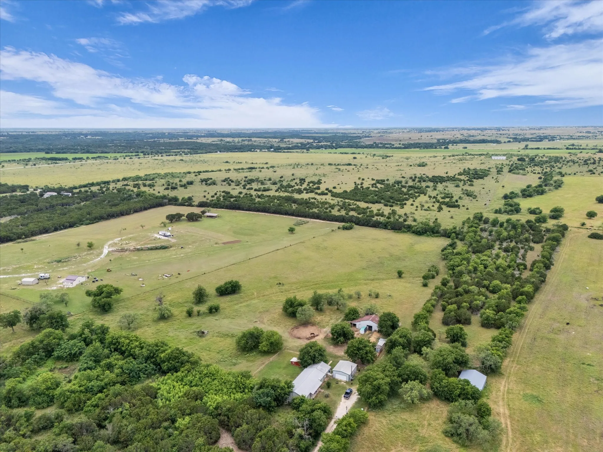 Expansive rural landscape featuring multiple structures, open fields, and mature tree lines