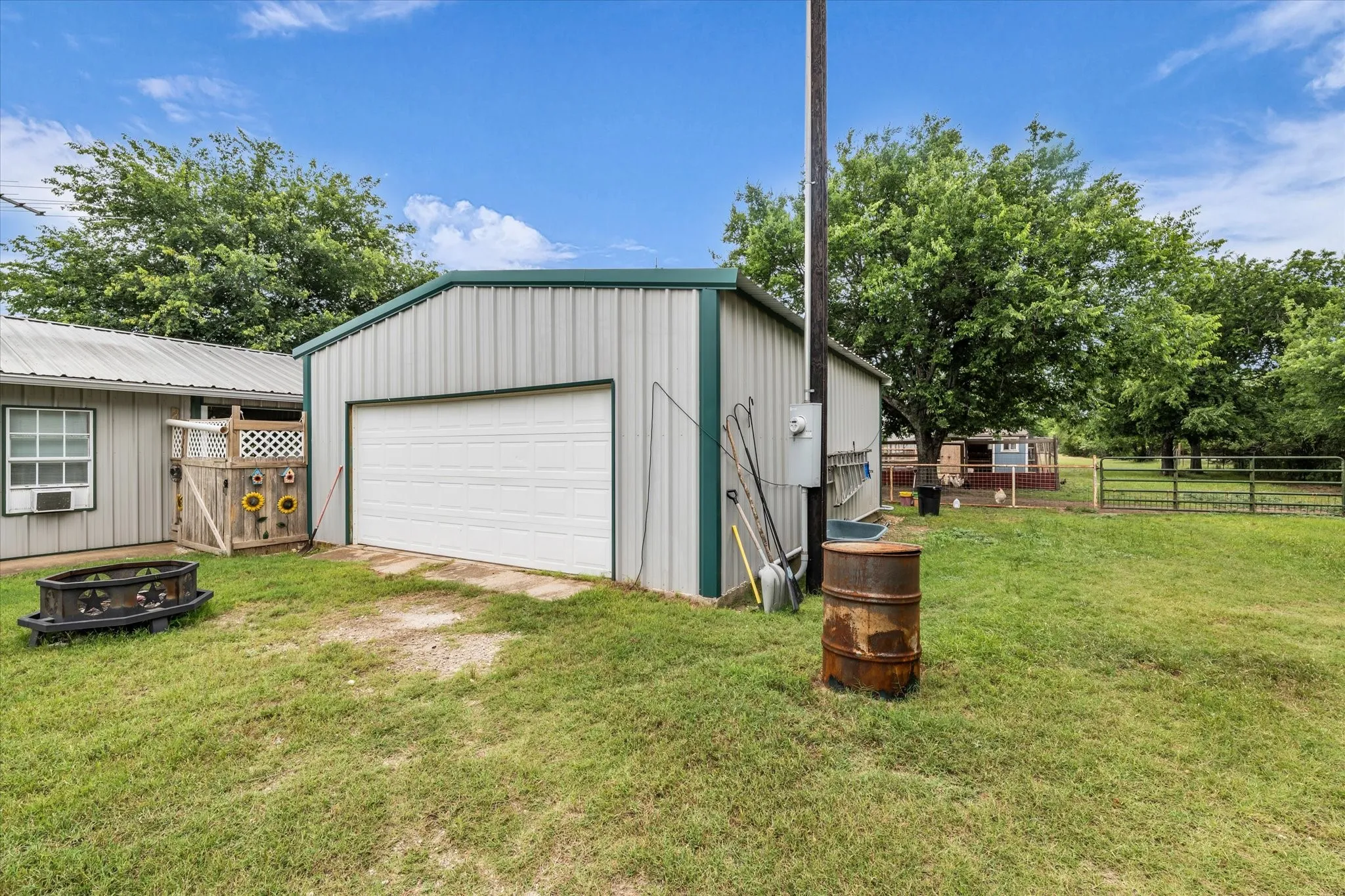 Detached metal building with a roll-up garage door, corrugated siding, and a green metal roof