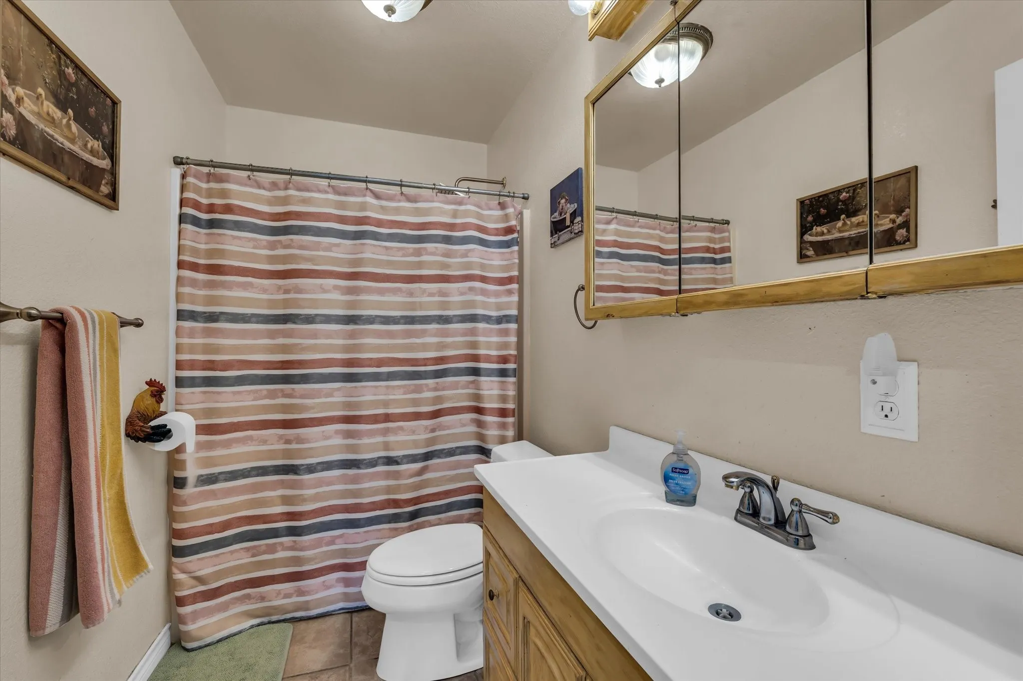 Bathroom featuring a single vanity with an integrated sink, a large wall-mounted mirror, and tile flooring