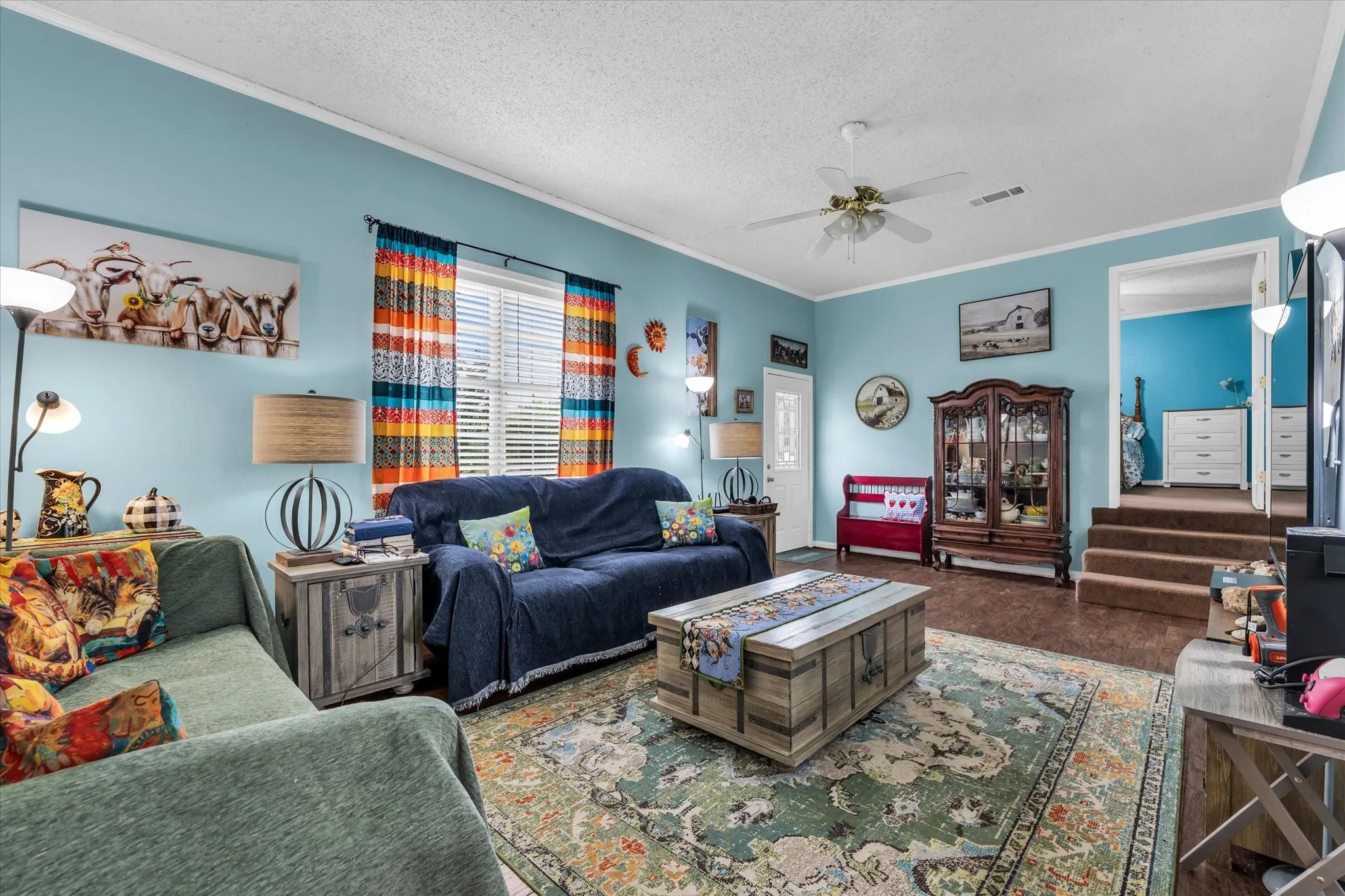Spacious living area featuring light blue walls, wood-finish flooring, and a ceiling fan