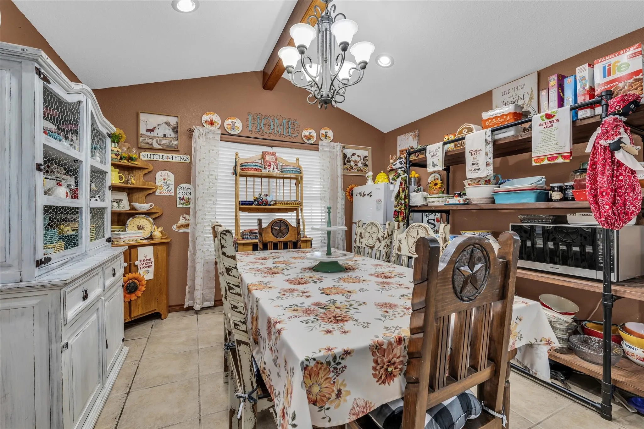 Dining area featuring vaulted ceilings with exposed wood beams, recessed lighting, and a chandelier