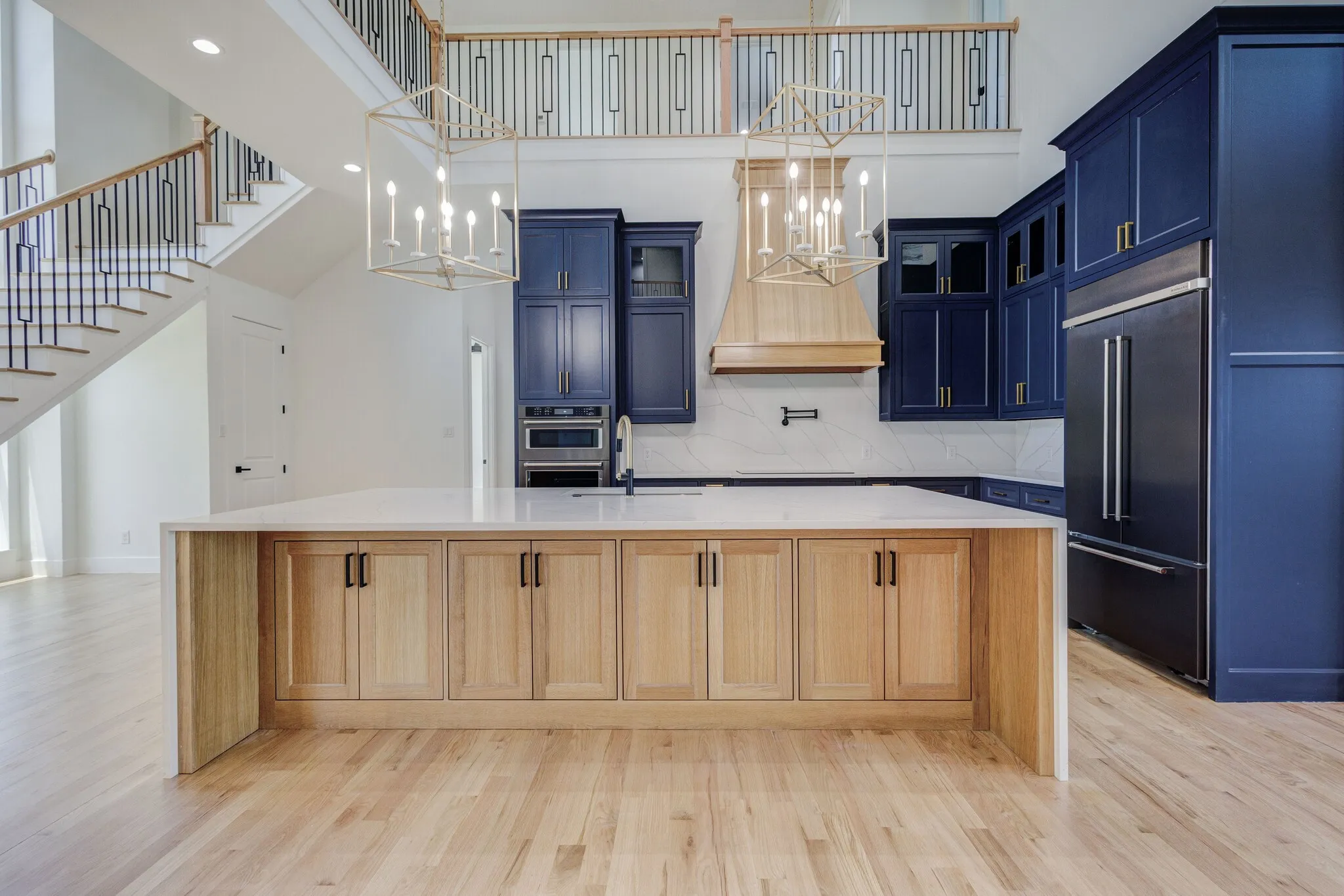 Open-concept kitchen featuring a large central island with light wood cabinetry and a white countertop