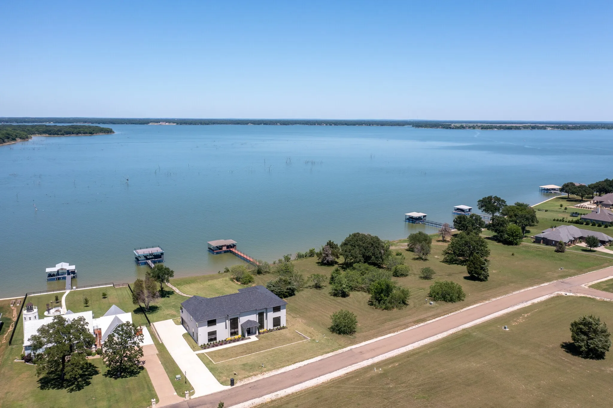 Waterfront property featuring a private boat dock, lush green landscaping, and mature trees