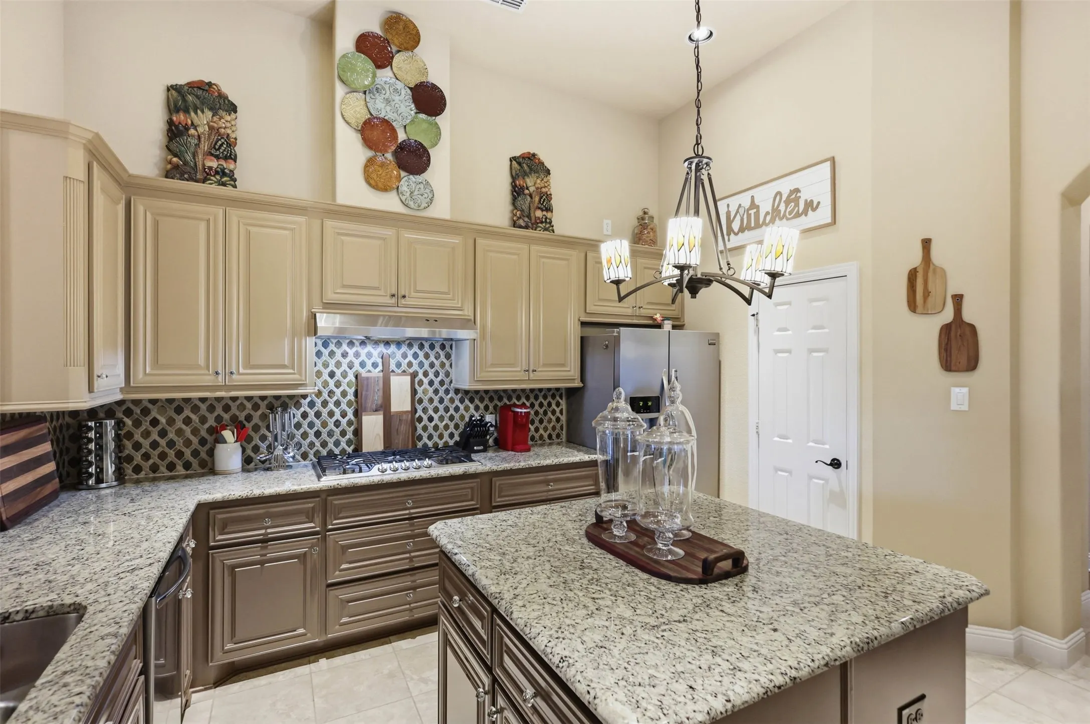 Spacious kitchen featuring an island, light-toned cabinetry, granite countertops, a built-in gas range, and a decorative tile backsplash