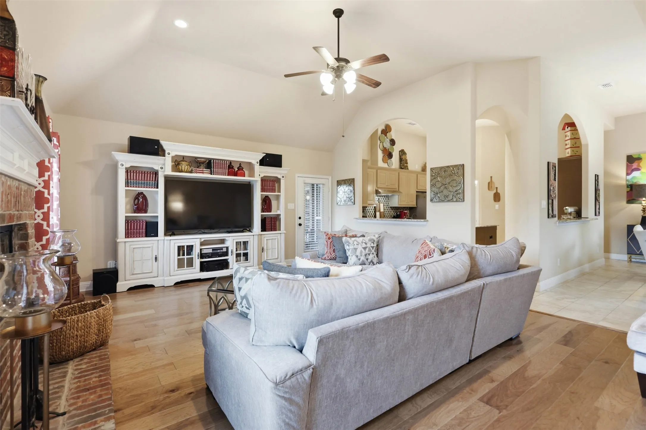Living area with vaulted ceilings, wood-finish flooring, and a ceiling fan